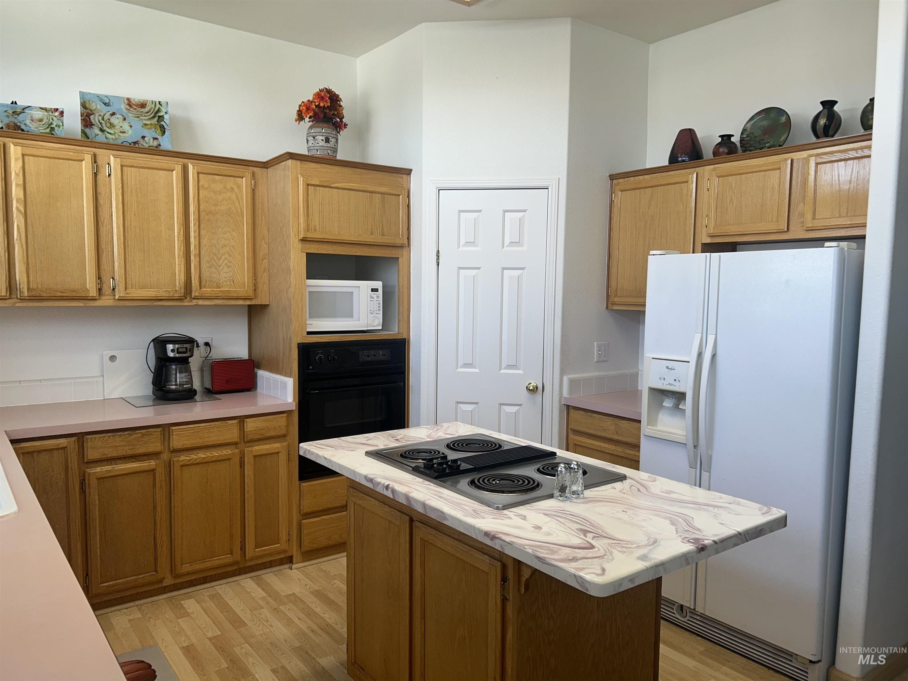 Kitchen featuring white appliances, light wood-style flooring, light countertops, and a center island