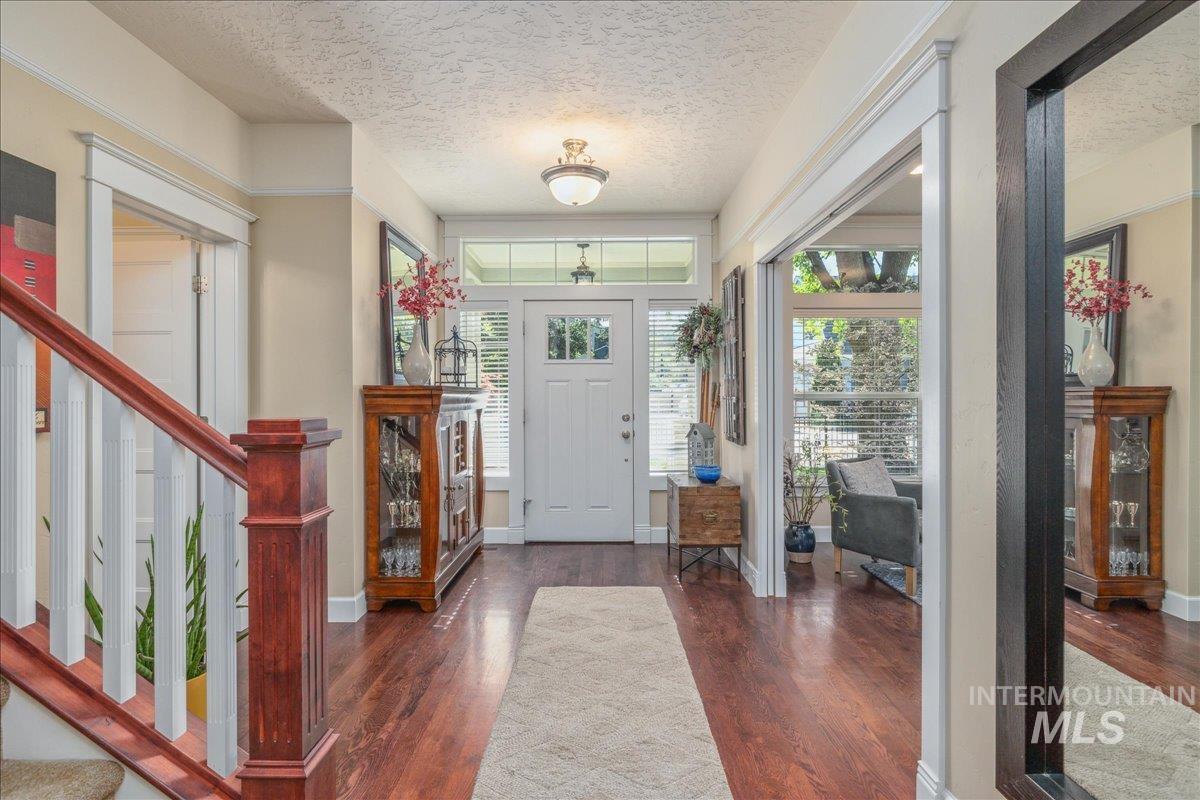 Foyer with stairs, dark wood-style flooring, and a textured ceiling
