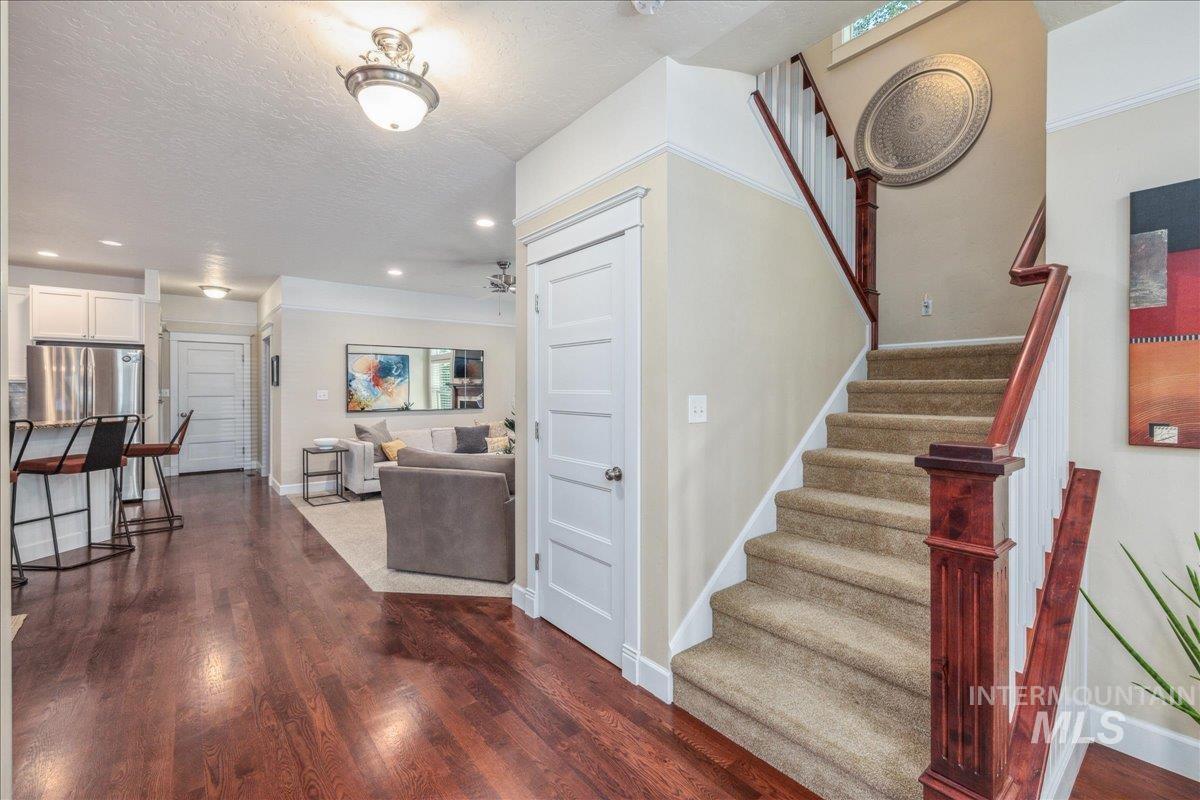 Stairs featuring a textured ceiling, wood finished floors, and recessed lighting