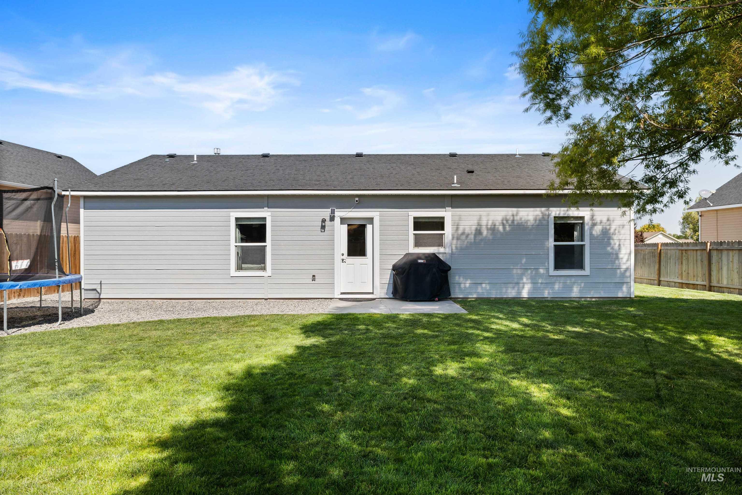 Back of house featuring a trampoline, a patio area, and a fenced backyard