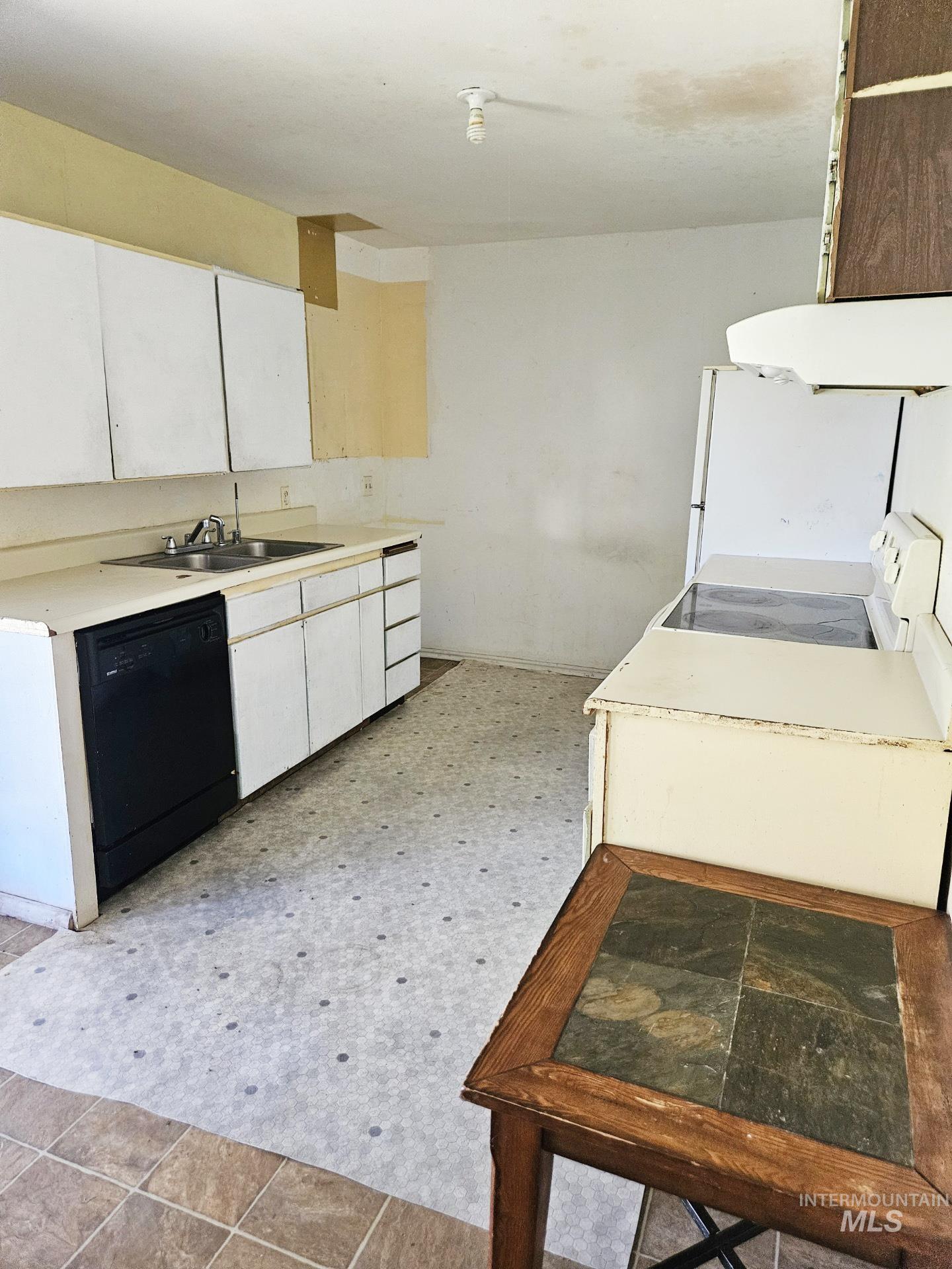 Kitchen featuring white cabinets, light countertops, white appliances, light floors, and extractor fan