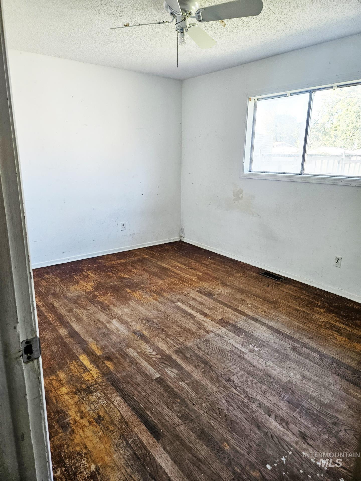 Unfurnished room with dark wood-type flooring and a textured ceiling