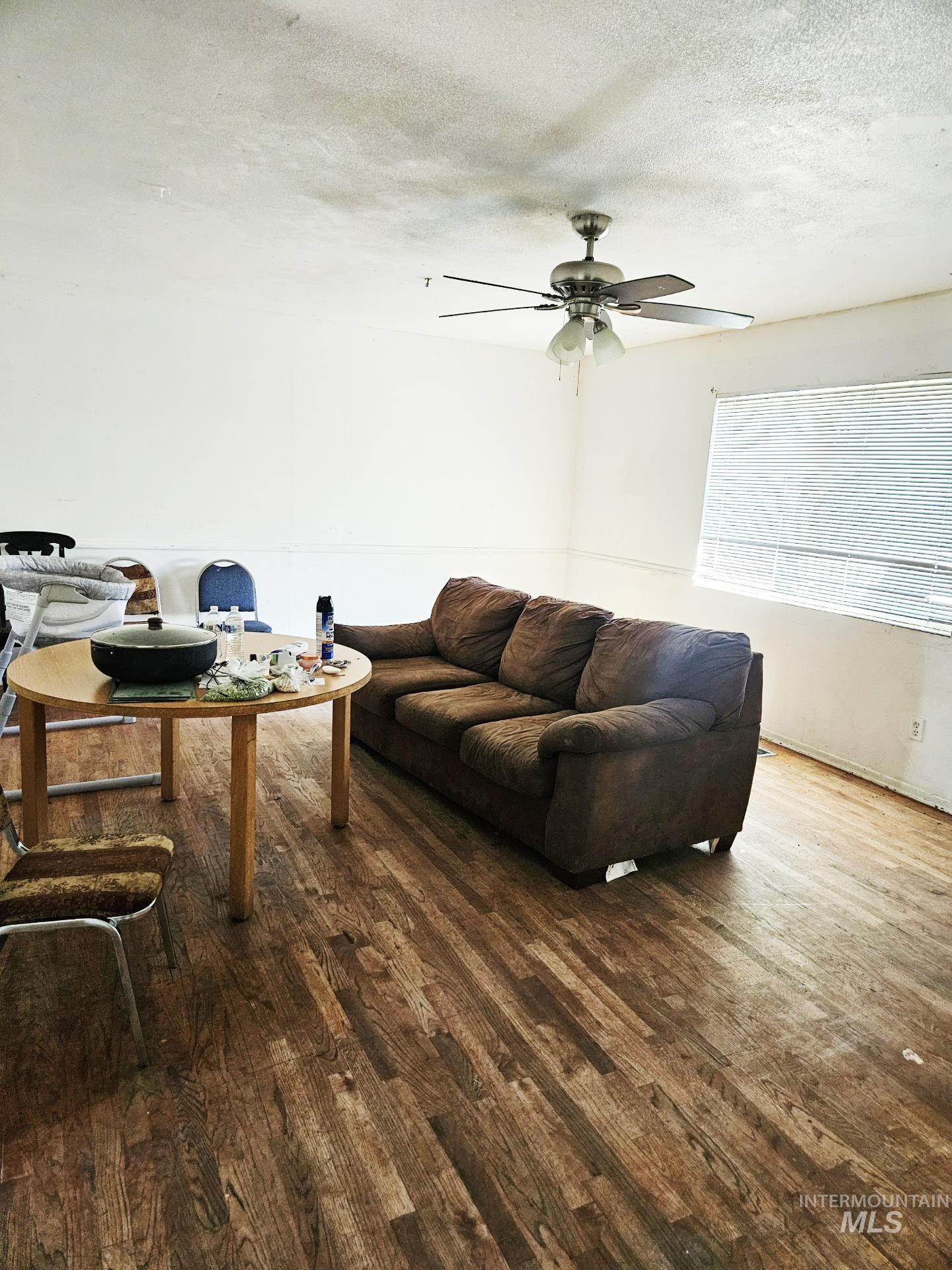Living area with a textured ceiling, wood finished floors, and a ceiling fan
