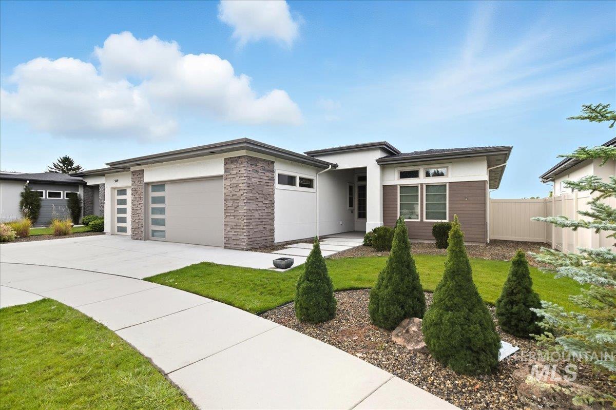 Prairie-style home with concrete driveway, an attached garage, stucco siding, and stone siding