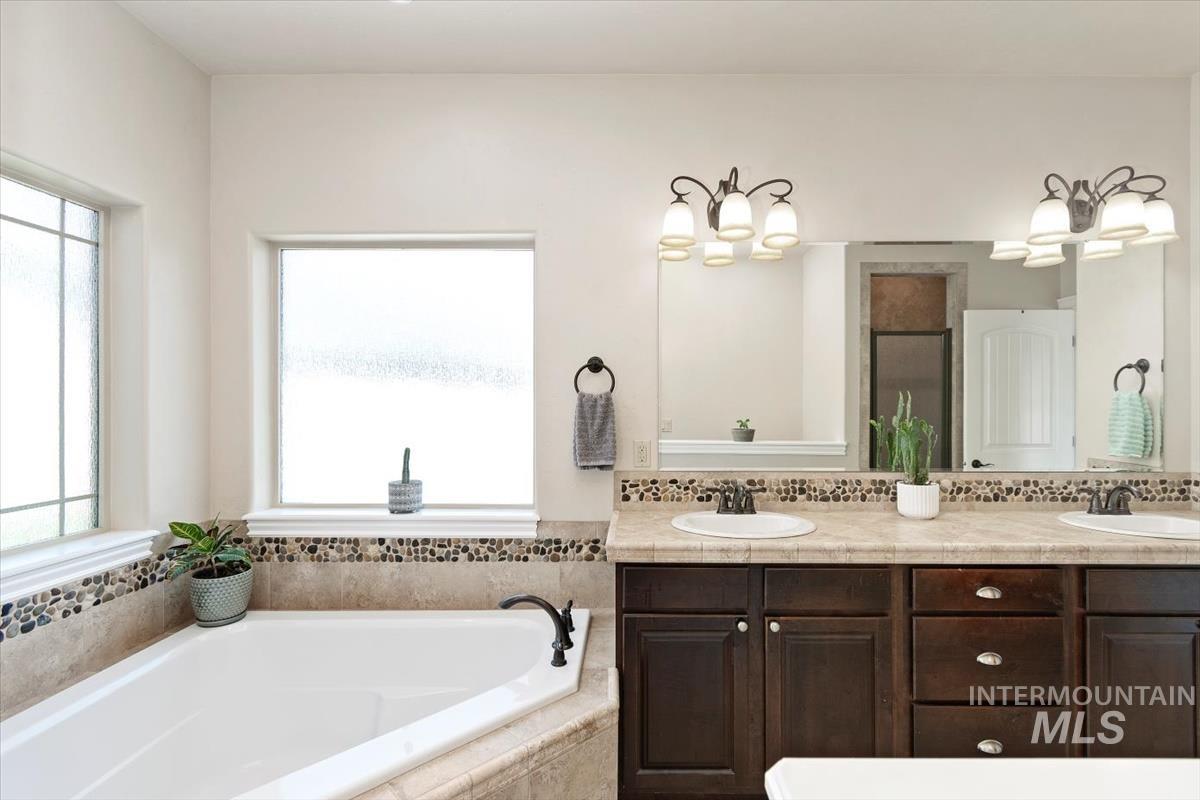 Full bathroom with double vanity, a bath, and healthy amount of natural light