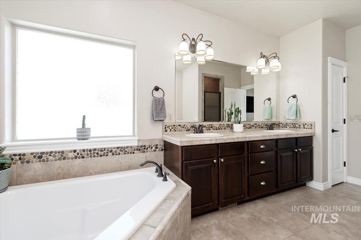 Full bathroom featuring double vanity, a bath, and light tile patterned floors