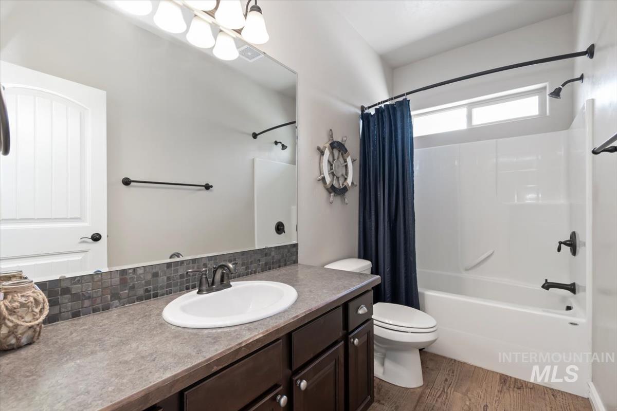 Bathroom featuring shower / bath combination with curtain, light wood finished floors, and vanity