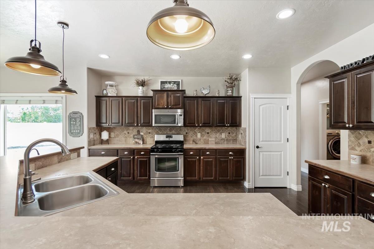 Kitchen with backsplash, light countertops, dark brown cabinetry, and recessed lighting