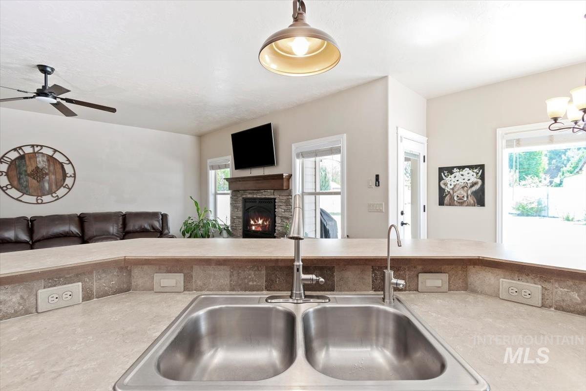 Kitchen featuring light countertops, a stone fireplace, open floor plan, and hanging light fixtures