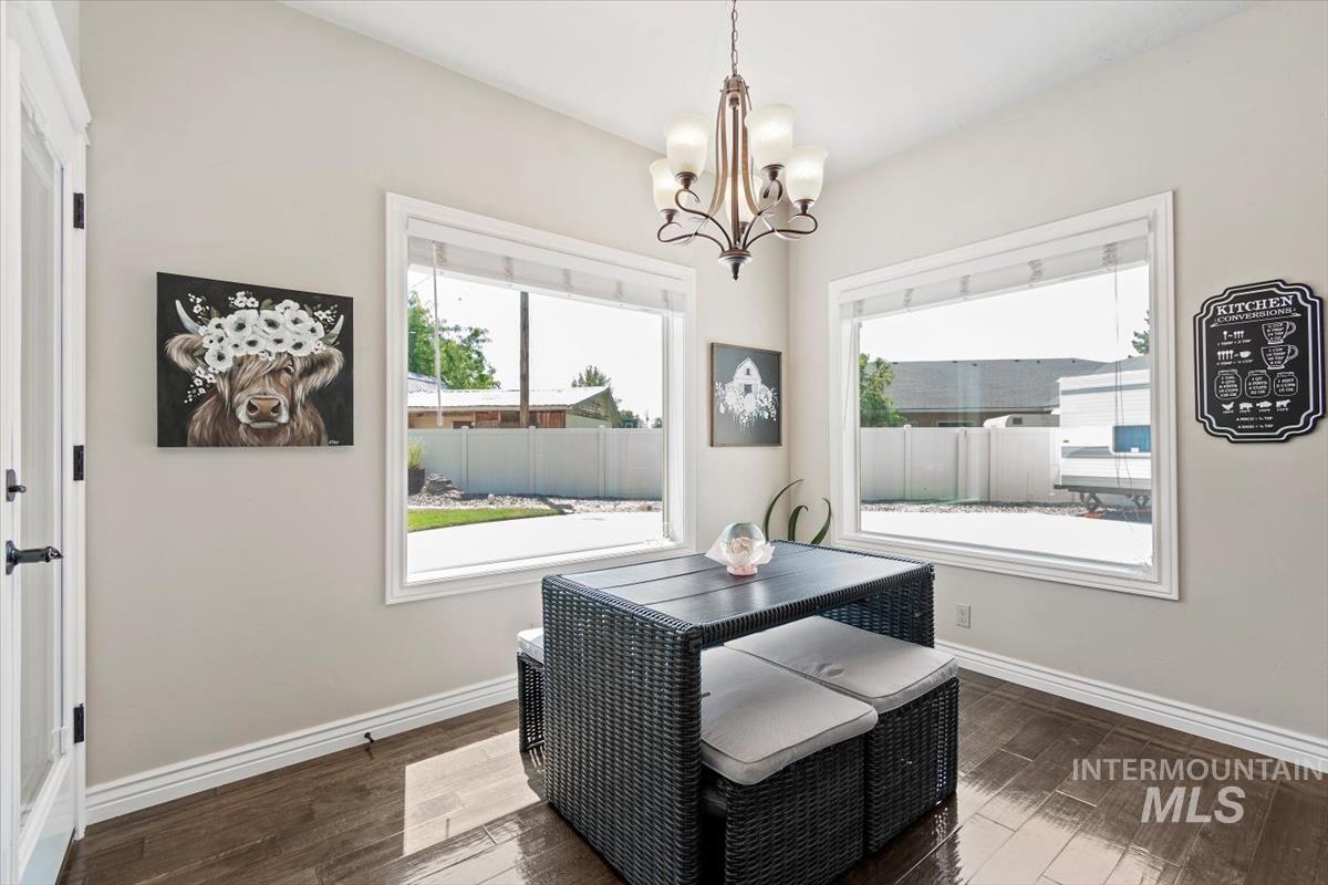 Dining room with dark wood-style floors and a chandelier