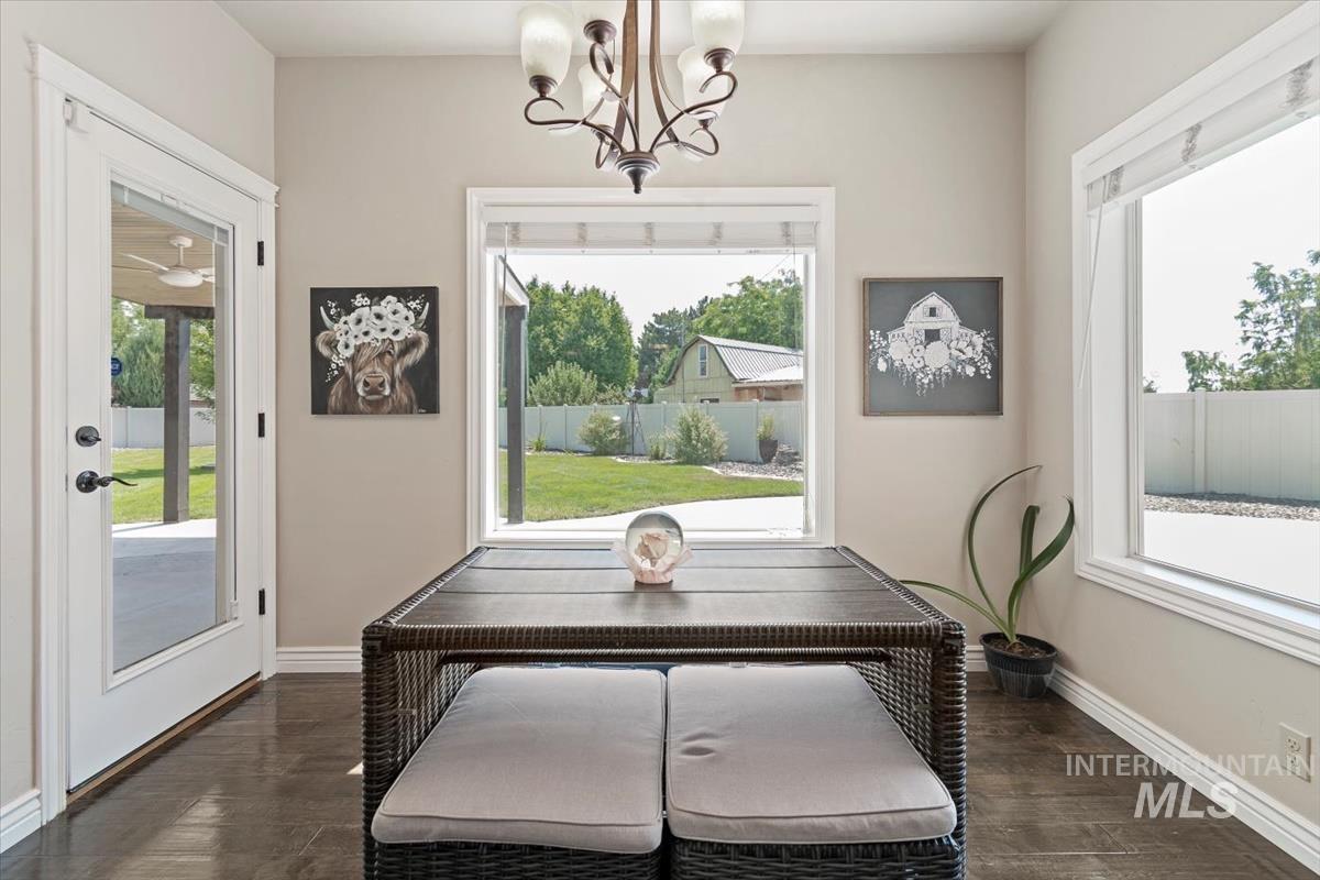 Dining area featuring dark wood-style floors, plenty of natural light, and a chandelier