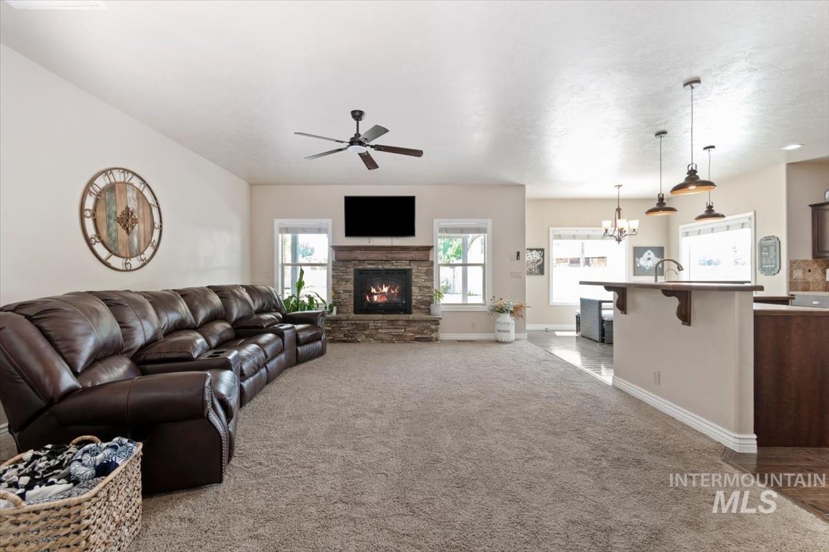Living area featuring light colored carpet, a fireplace, ceiling fan, and a chandelier
