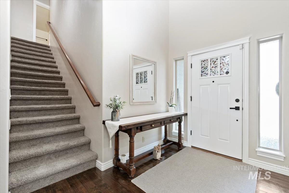 Entryway featuring dark wood-style flooring, stairs, and a towering ceiling