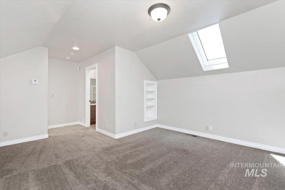 Additional living space with lofted ceiling, carpet, a skylight, and built in features