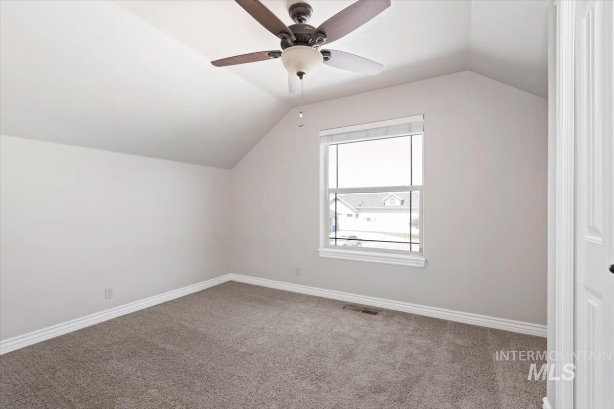 Additional living space with lofted ceiling, carpet floors, and a ceiling fan