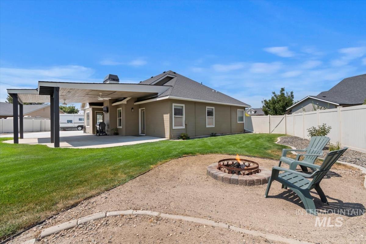 Rear view of property with a patio area, an outdoor fire pit, a fenced backyard, and a chimney