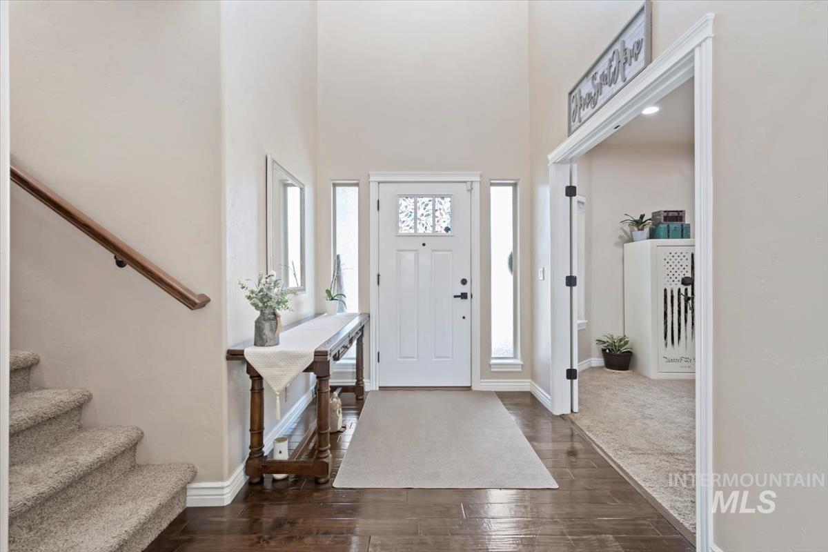 Foyer entrance with dark wood-type flooring, stairs, and a towering ceiling