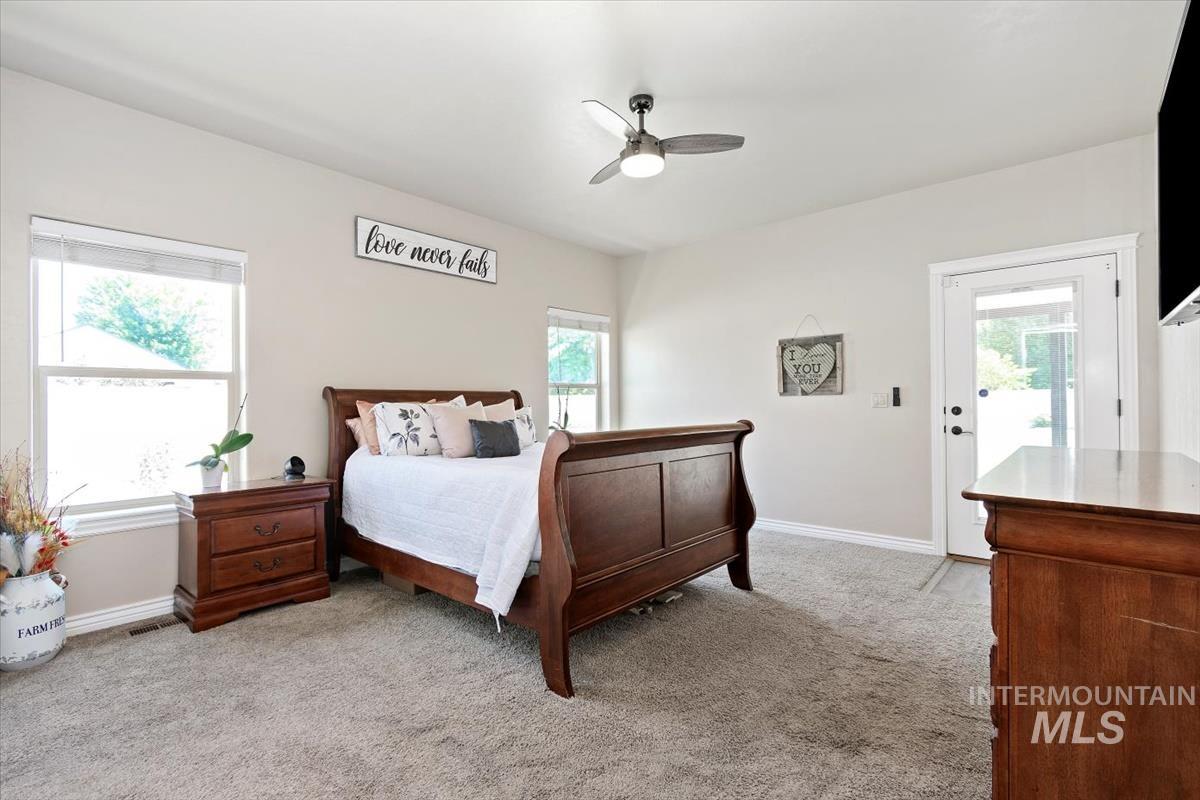 Bedroom featuring light carpet, multiple windows, a ceiling fan, and access to outside