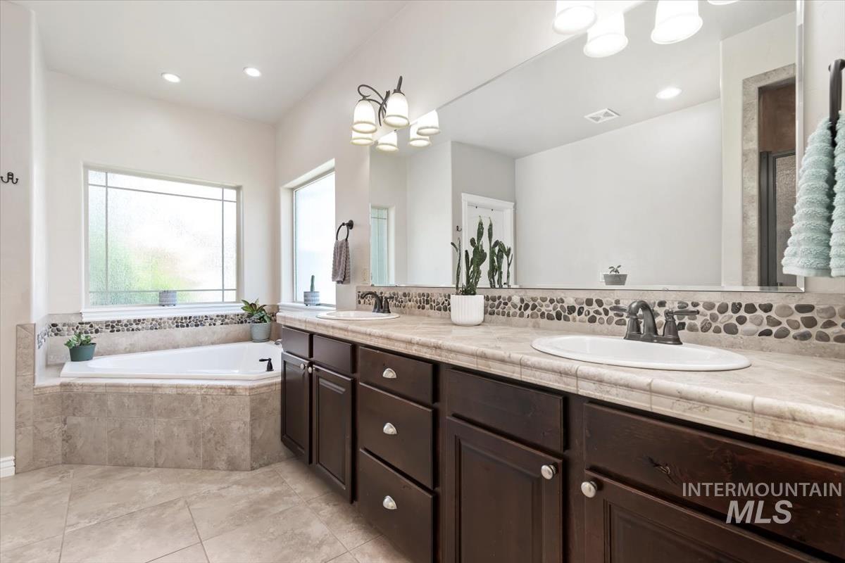 Bathroom featuring a bath, double vanity, light tile patterned flooring, recessed lighting, and a chandelier