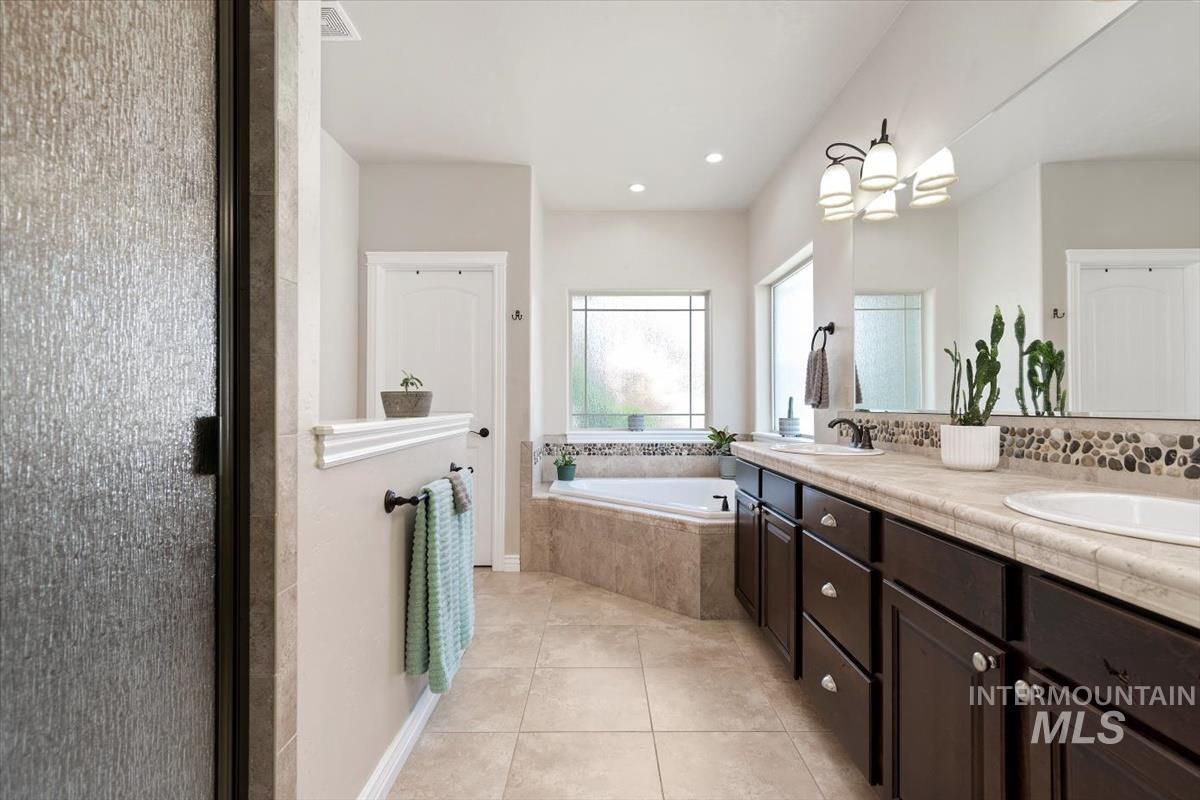 Full bathroom featuring double vanity, a bath, light tile patterned flooring, recessed lighting, and a stall shower