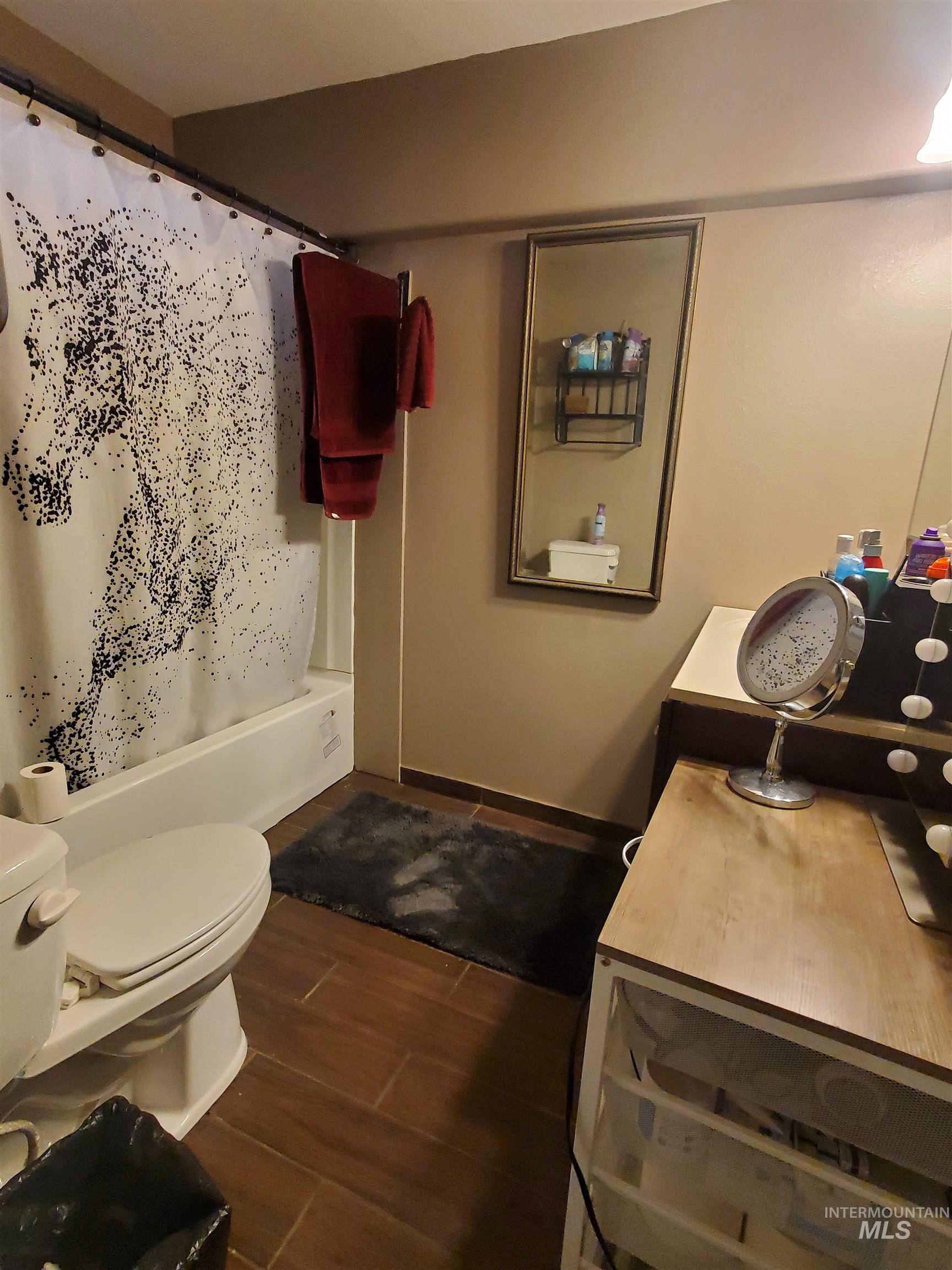 Bathroom featuring wood tiled floors, vanity, and shower / tub combo with curtain