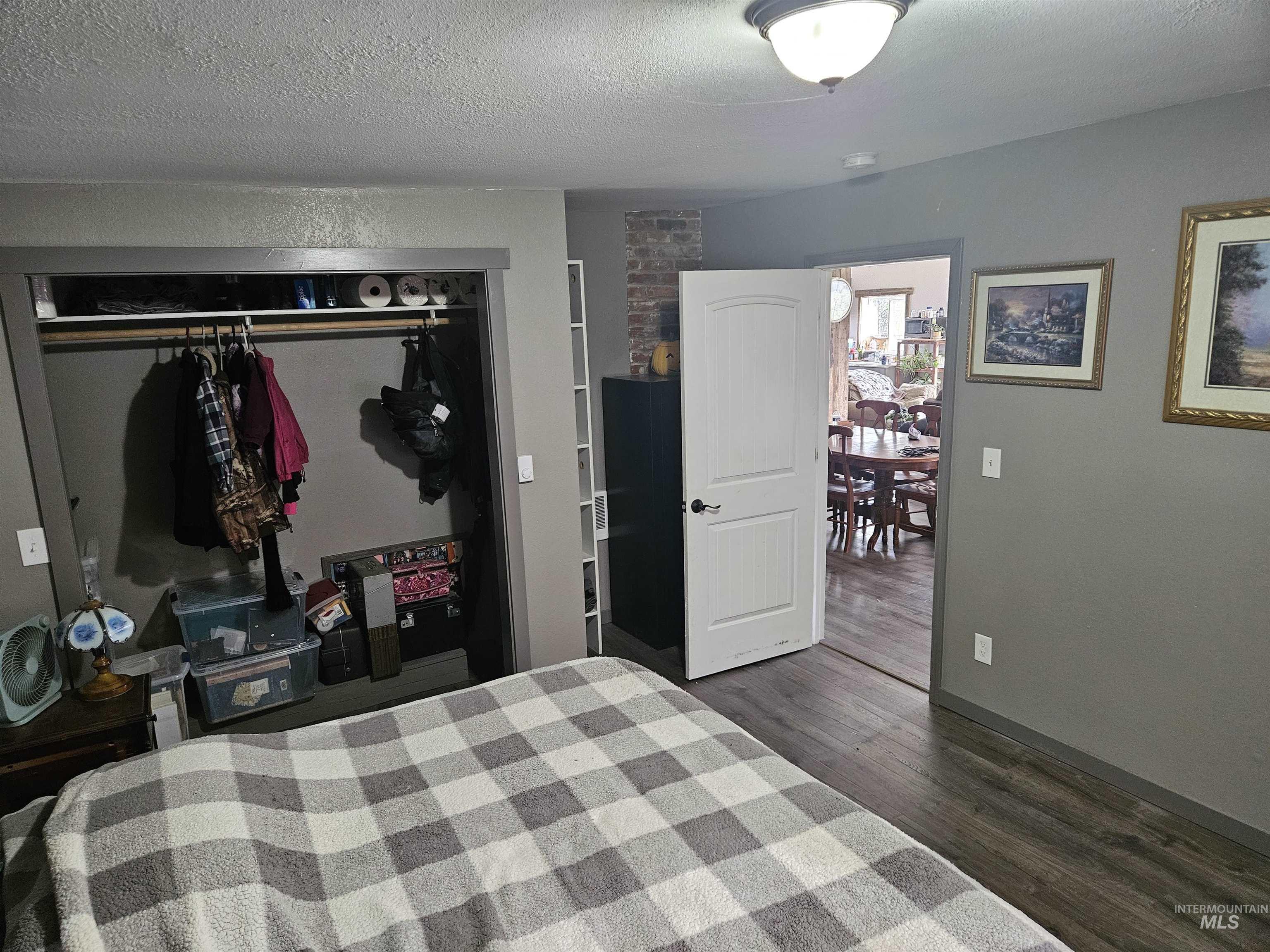 Bedroom featuring a closet, a textured ceiling, and dark wood-type flooring
