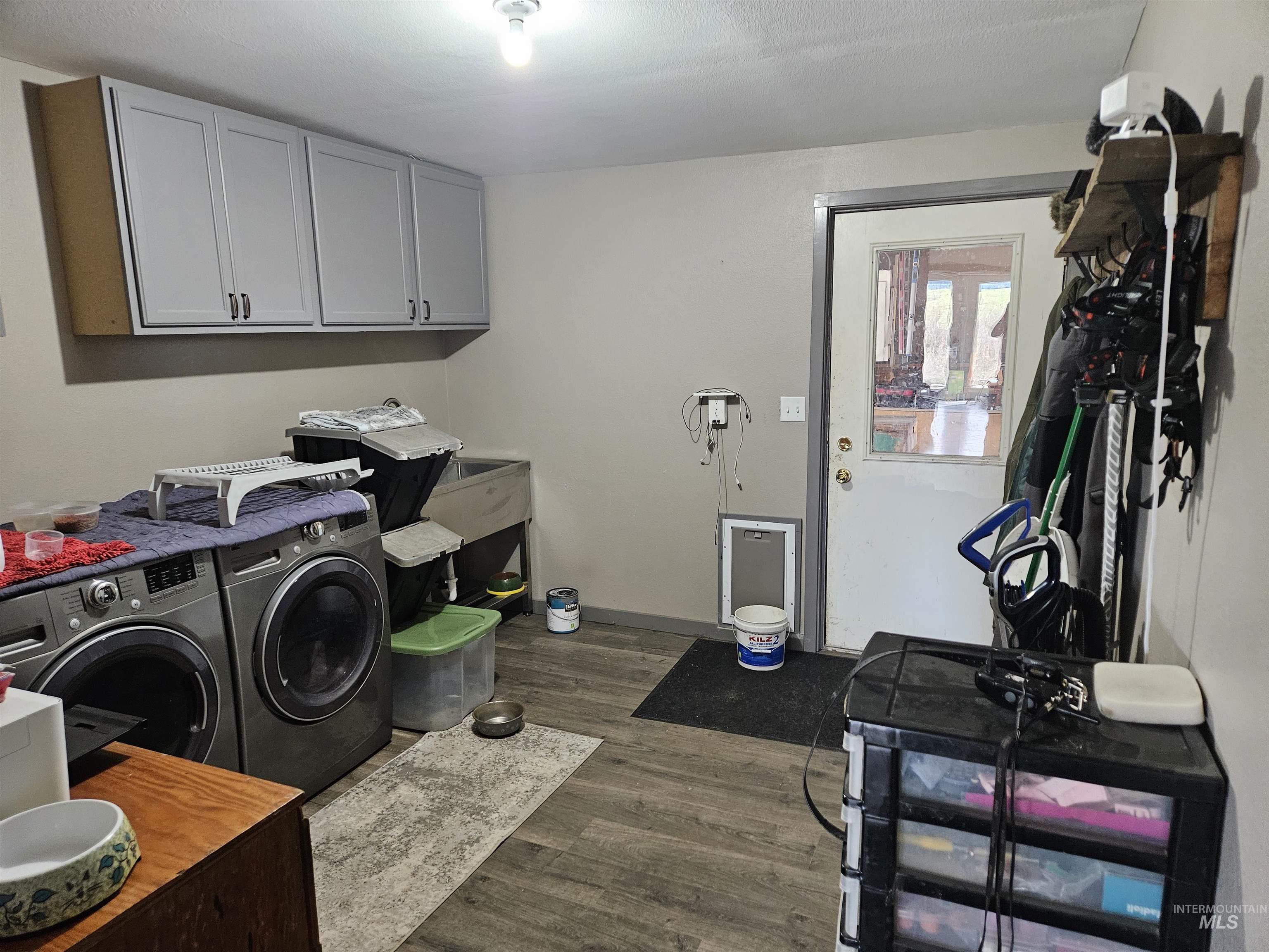 Laundry room featuring dark wood-type flooring, washer and dryer, and cabinet space