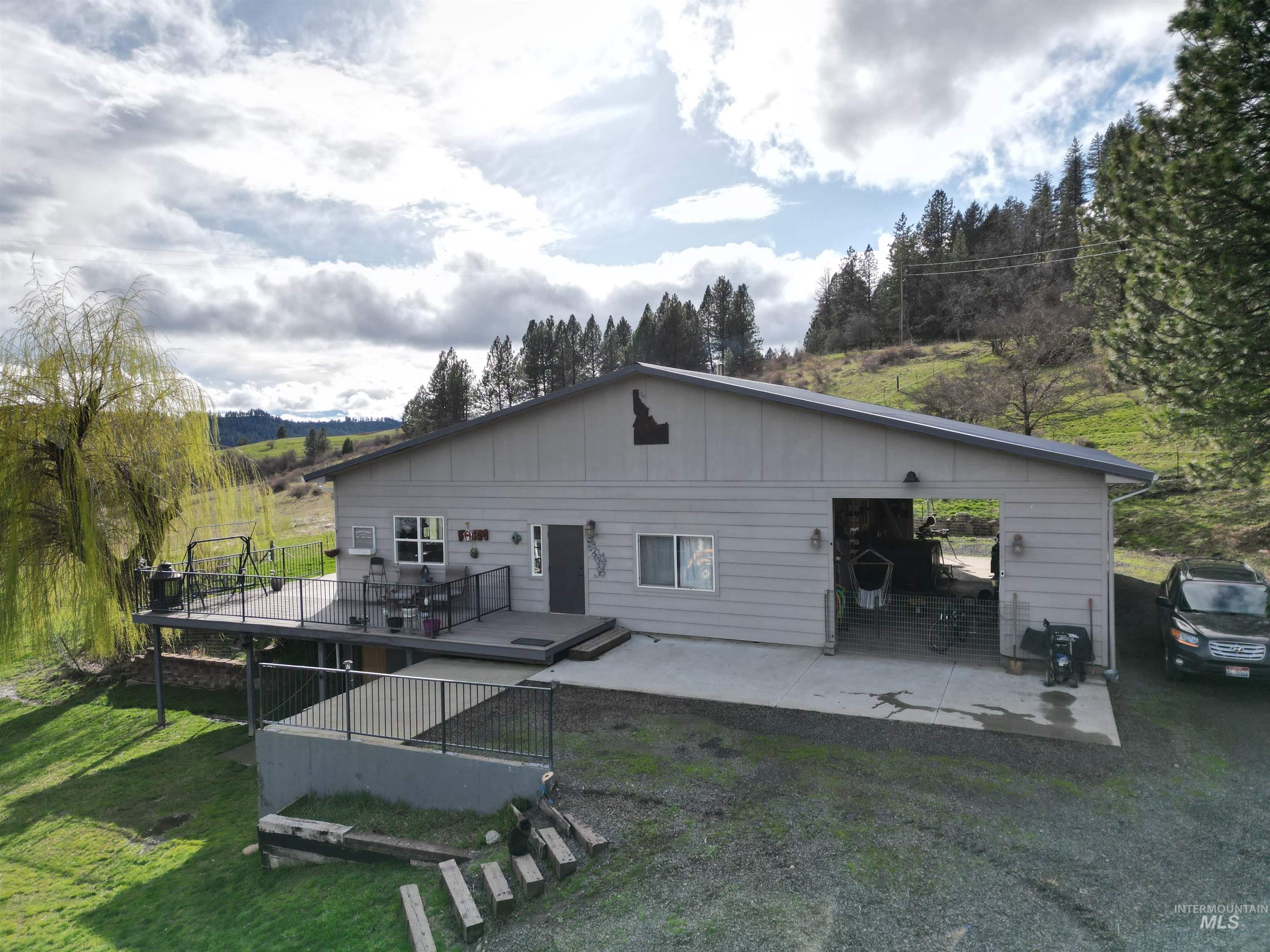 Rear view of house featuring a lawn, a deck, a patio area, and board and batten siding