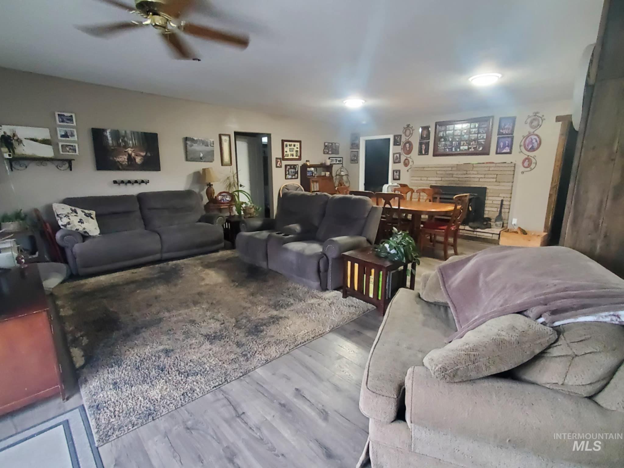 Living room featuring a stone fireplace, wood finished floors, and ceiling fan