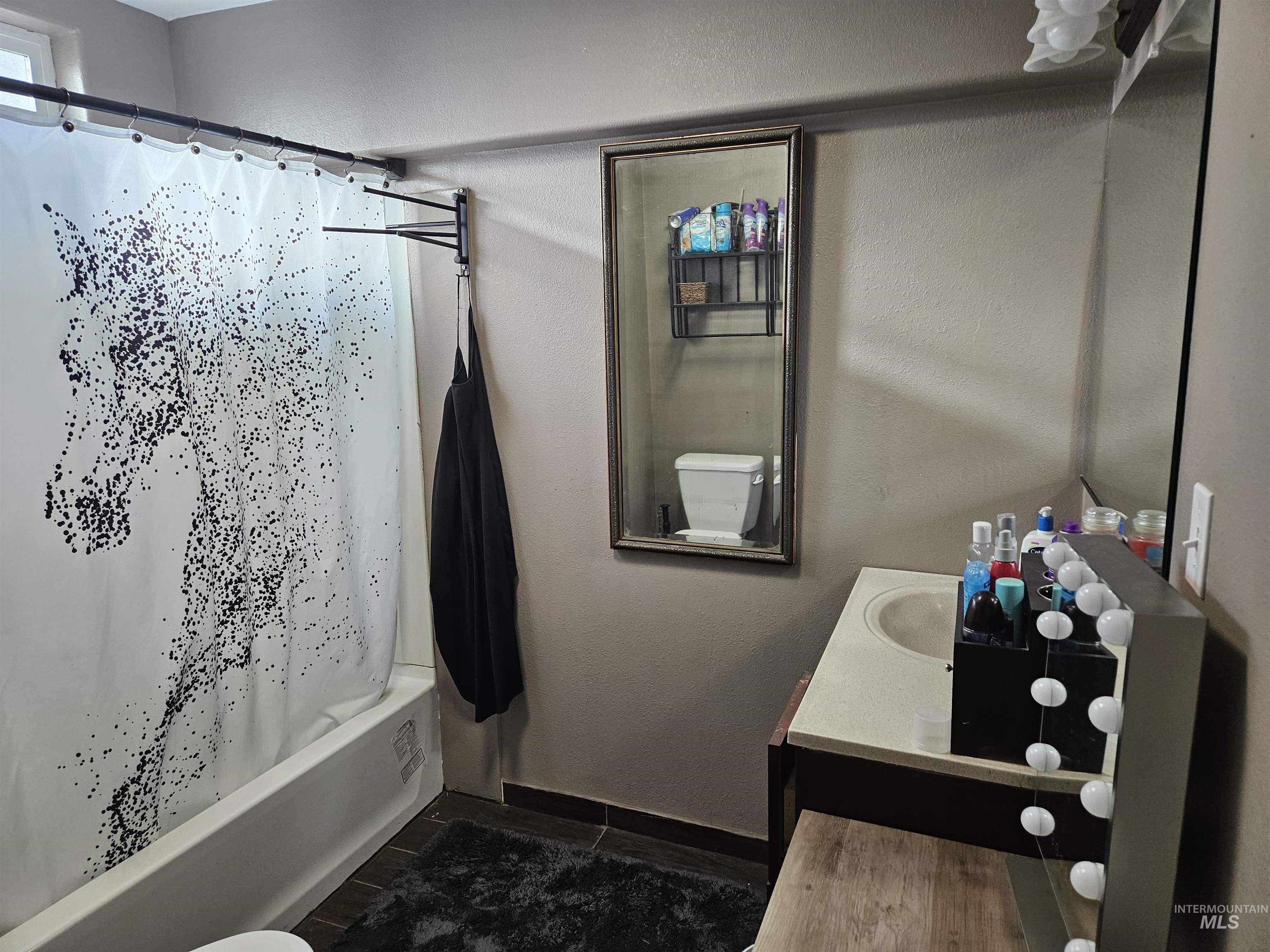Bathroom featuring shower / tub combo with curtain, vanity, dark wood-style flooring, and a textured wall
