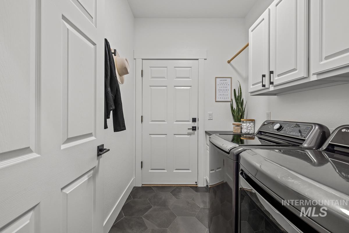 Laundry room with washing machine and dryer, dark tile patterned flooring, and cabinet space