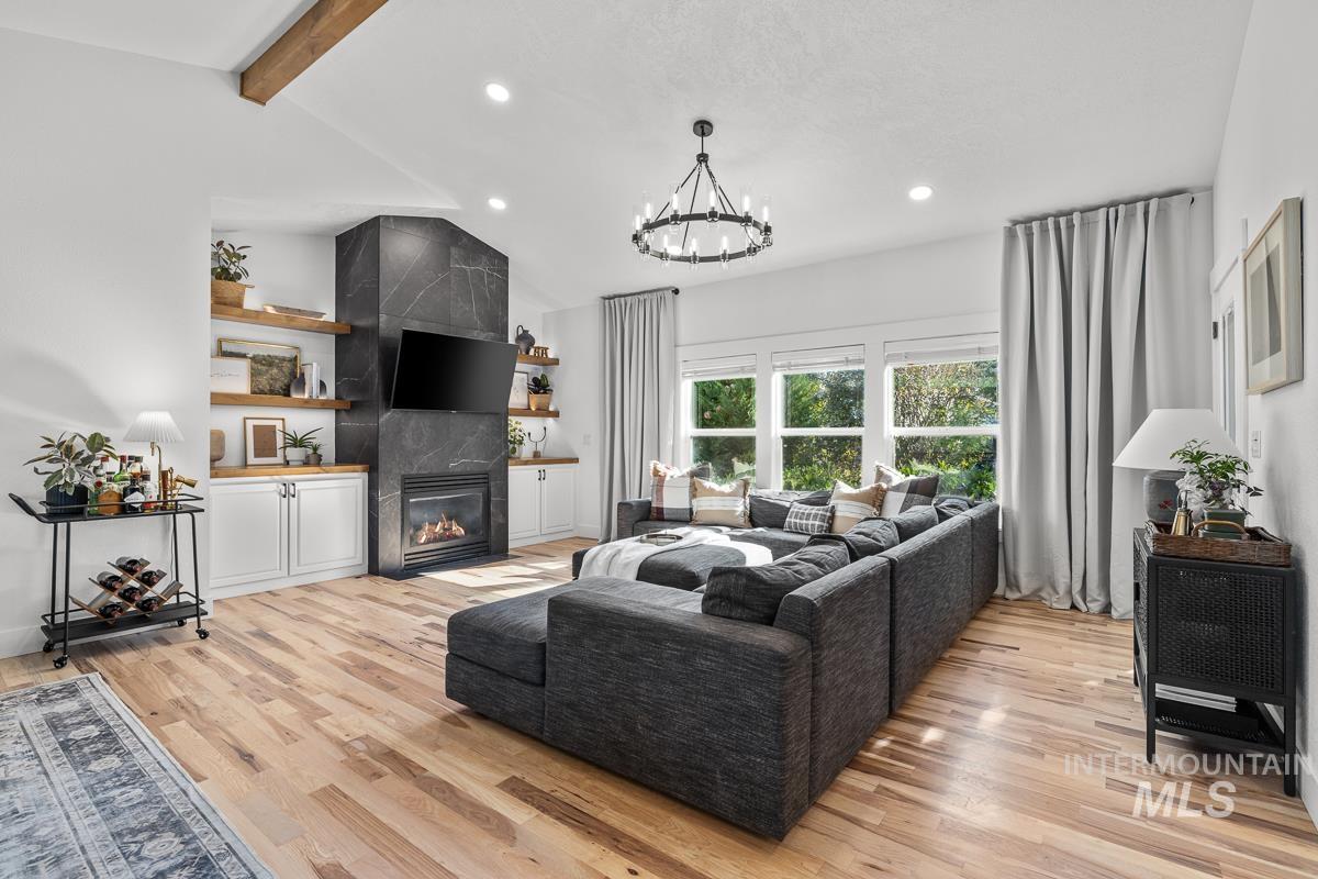 Living room with a tiled fireplace, light wood-style flooring, a chandelier, and recessed lighting