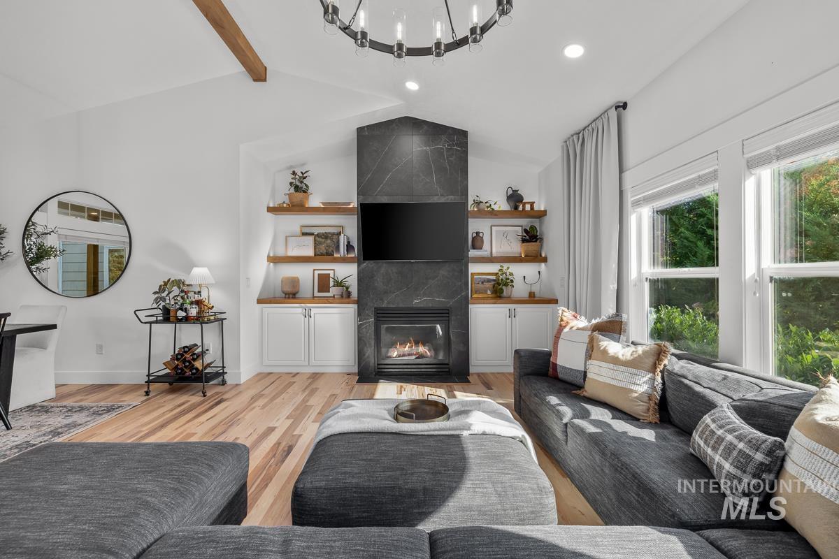 Living room with light wood-style flooring, a tiled fireplace, and recessed lighting