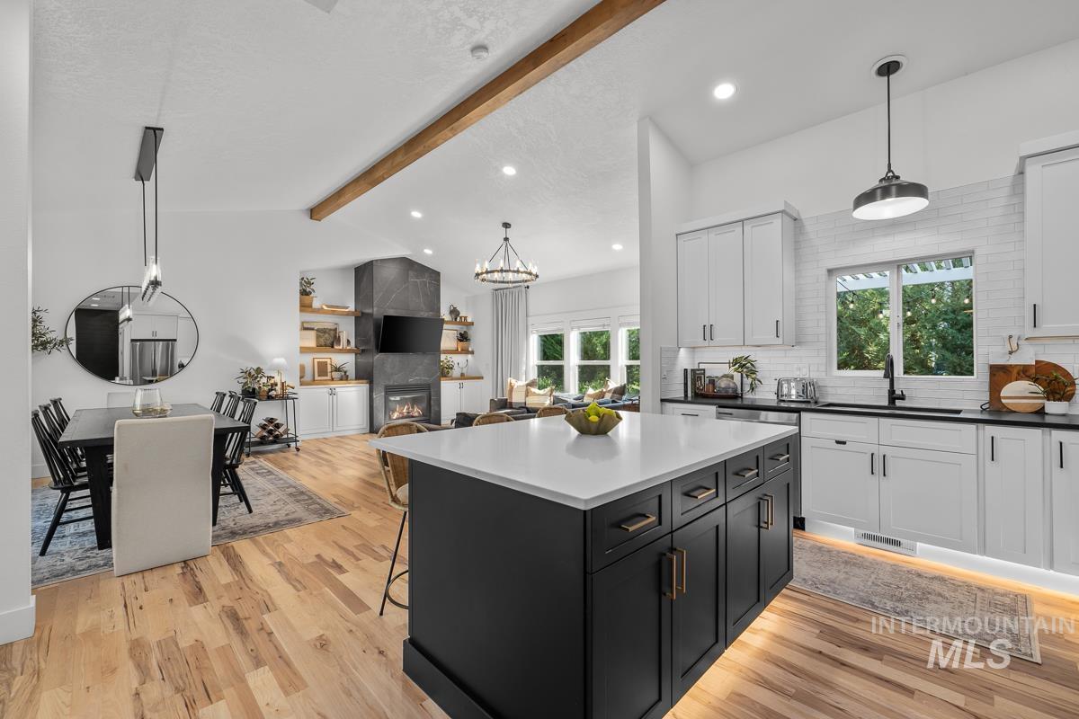 Kitchen with dark cabinetry, hanging light fixtures, a kitchen bar, tasteful backsplash, and a fireplace