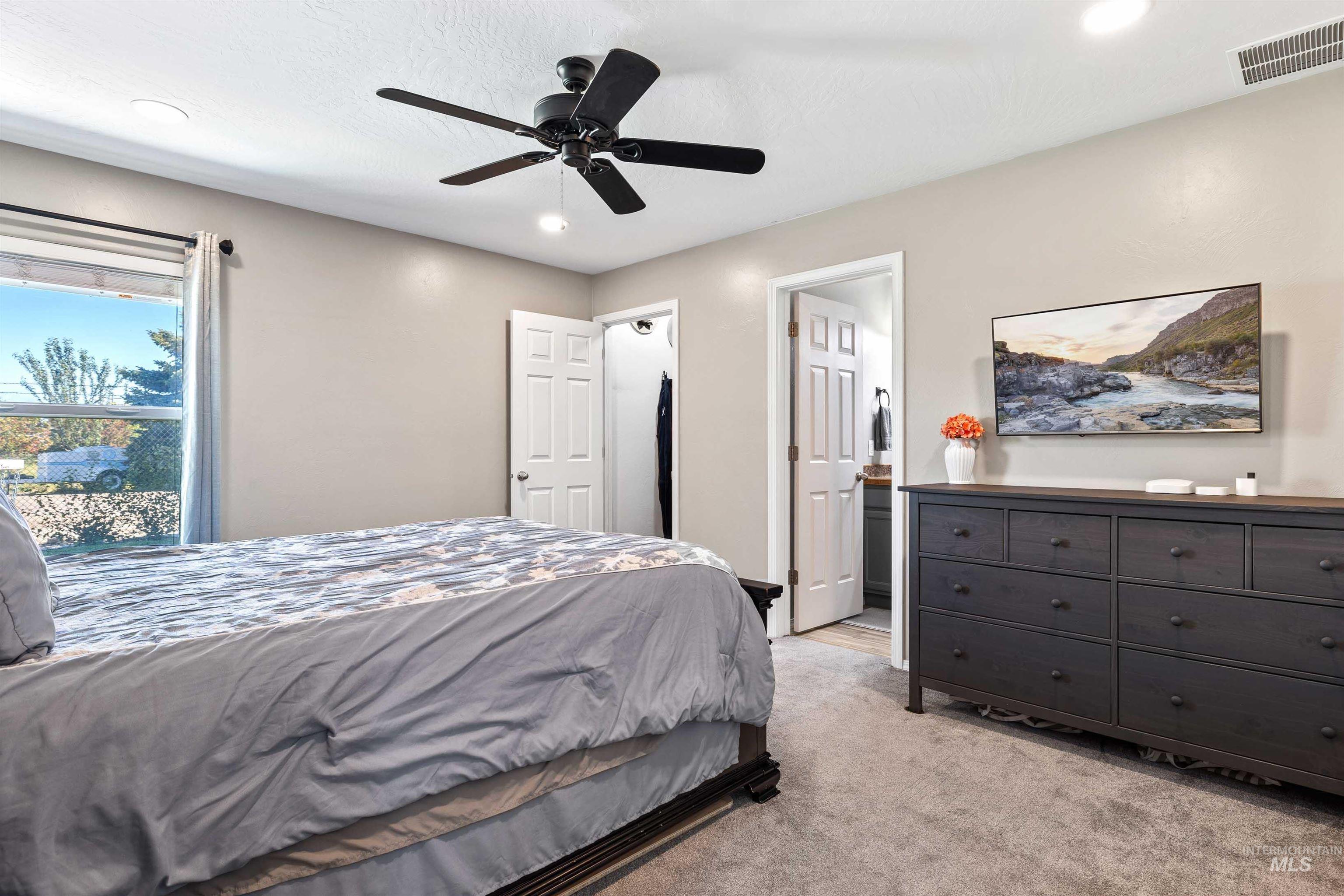 Bedroom with light colored carpet, ceiling fan, recessed lighting, and ensuite bath