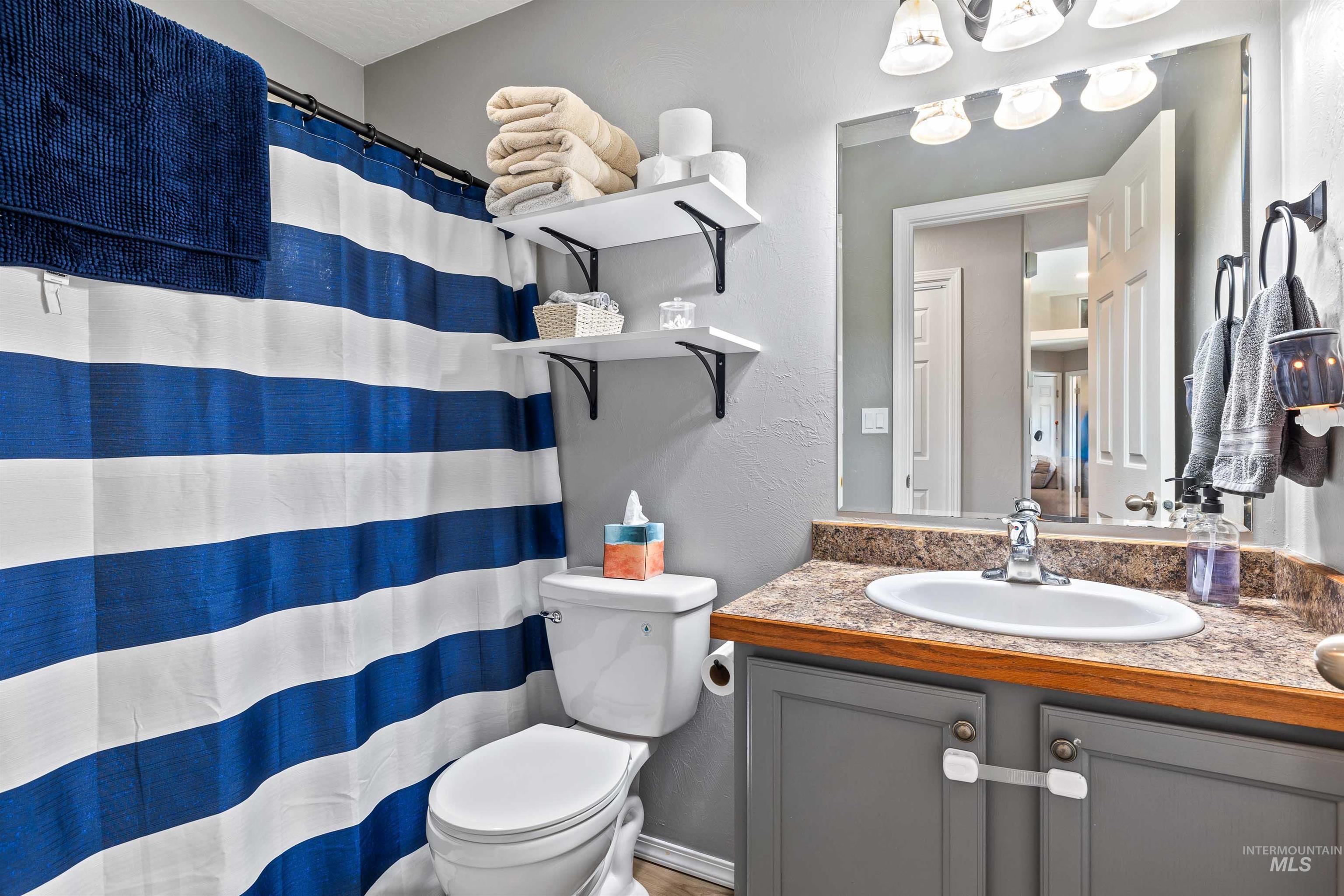 Full bath with a textured wall, vanity, and a shower with curtain
