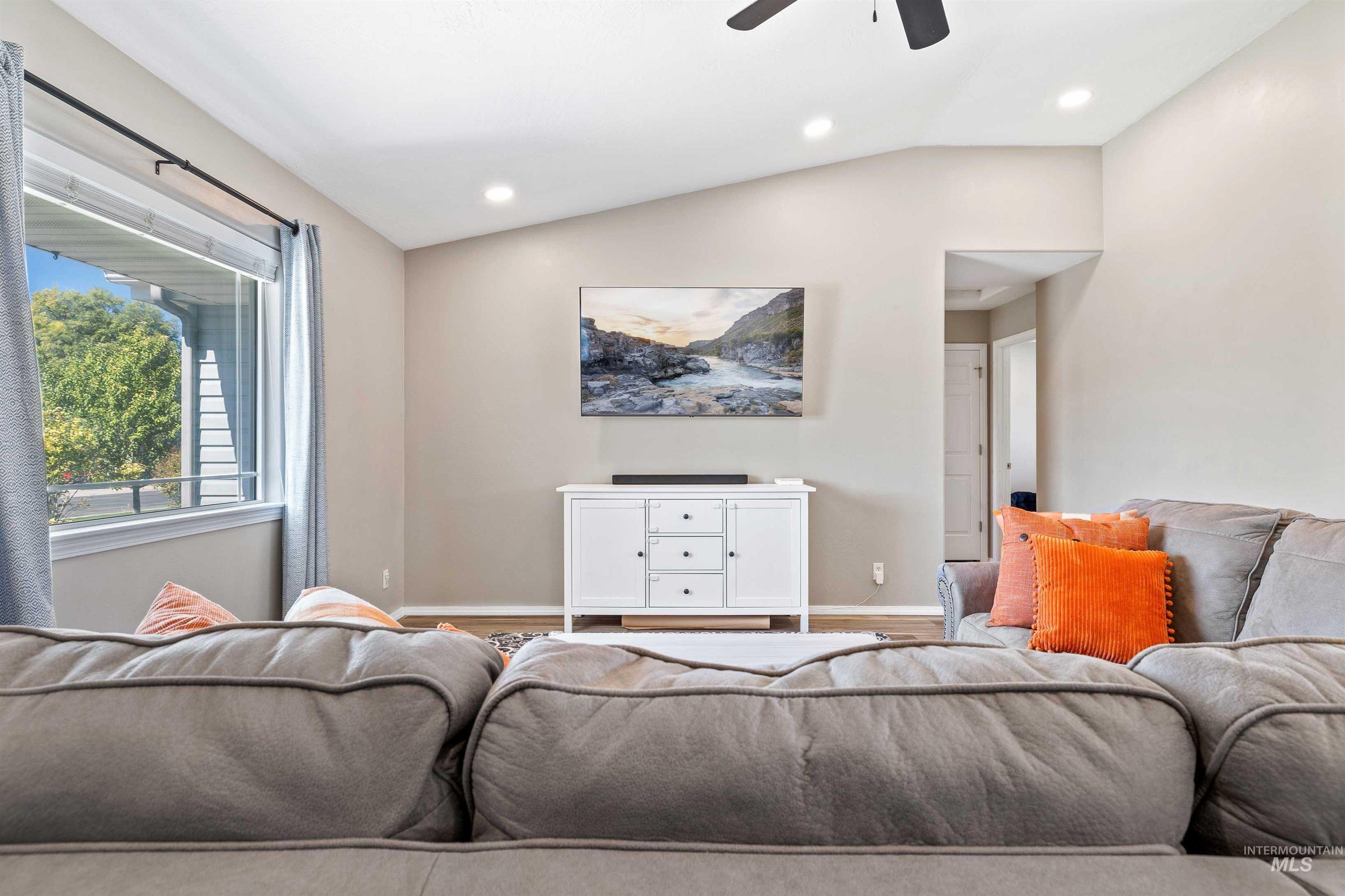 Living area with lofted ceiling, a ceiling fan, recessed lighting, and wood finished floors