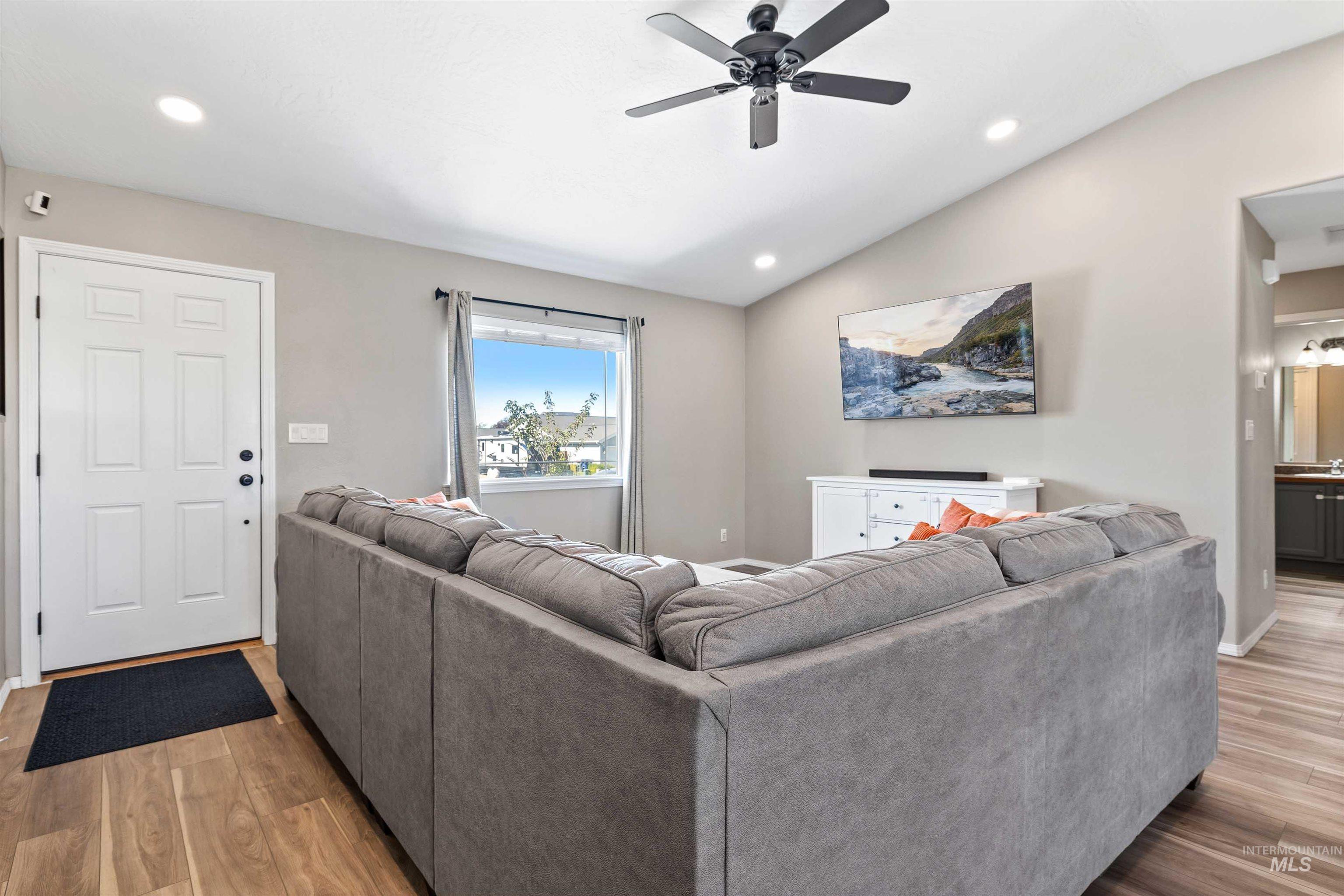Living room featuring lofted ceiling, recessed lighting, light wood-style flooring, and a ceiling fan