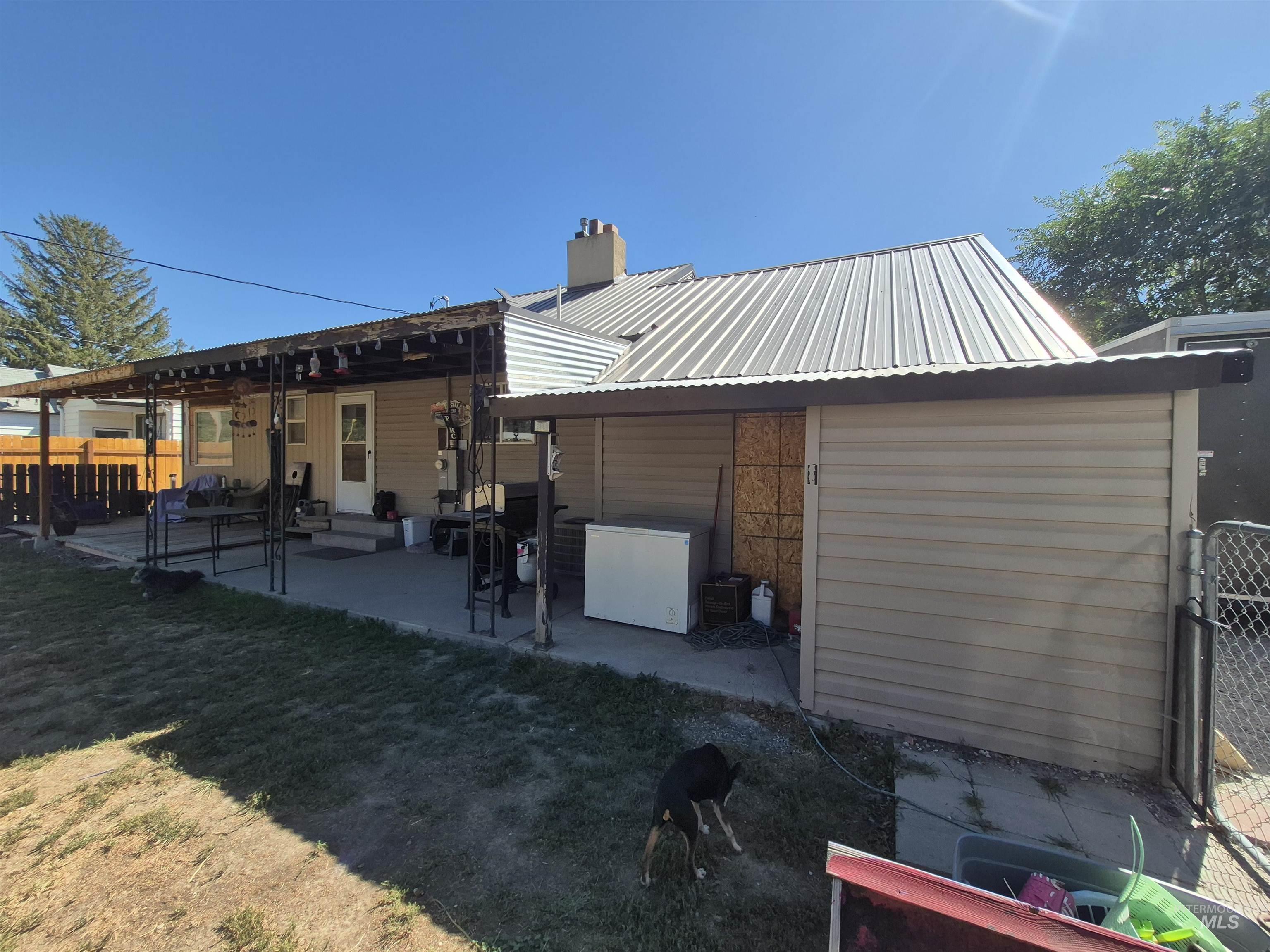 Rear view of house with a patio area, a metal roof, and a chimney