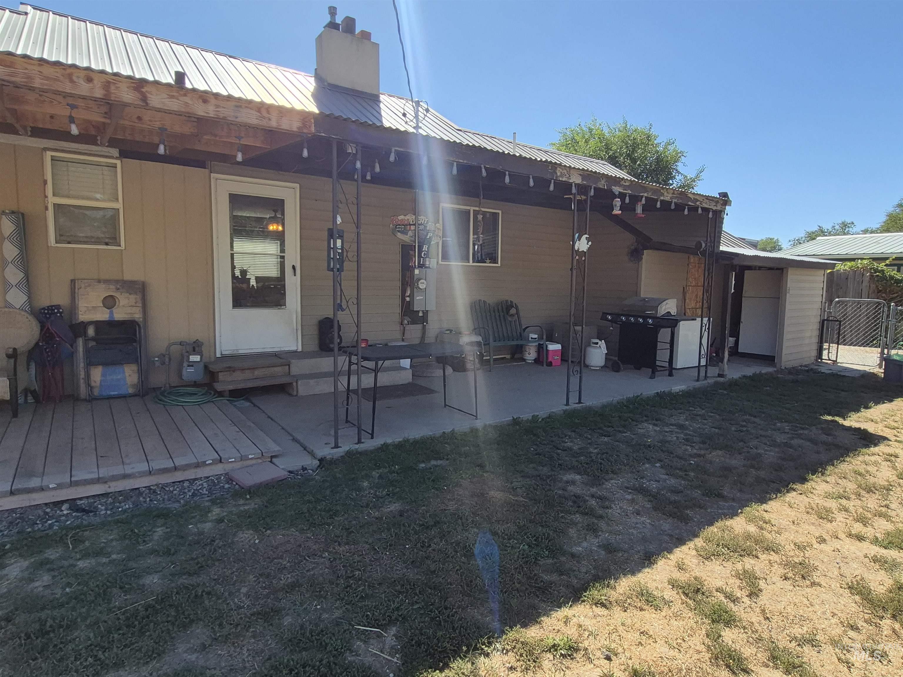 Rear view of house featuring a patio area, a metal roof, a chimney, and a lawn