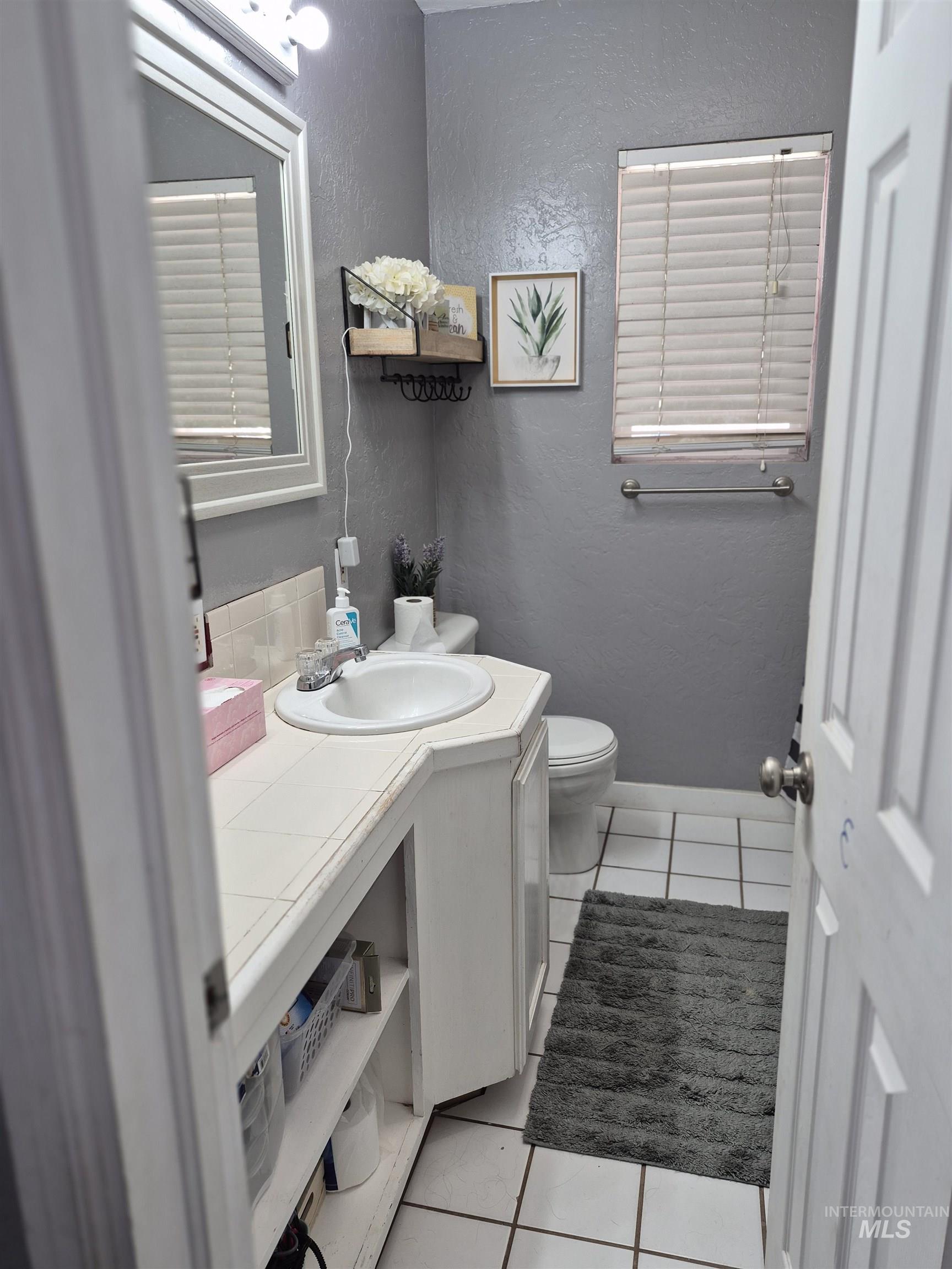 Bathroom featuring a textured wall, light tile patterned floors, and vanity