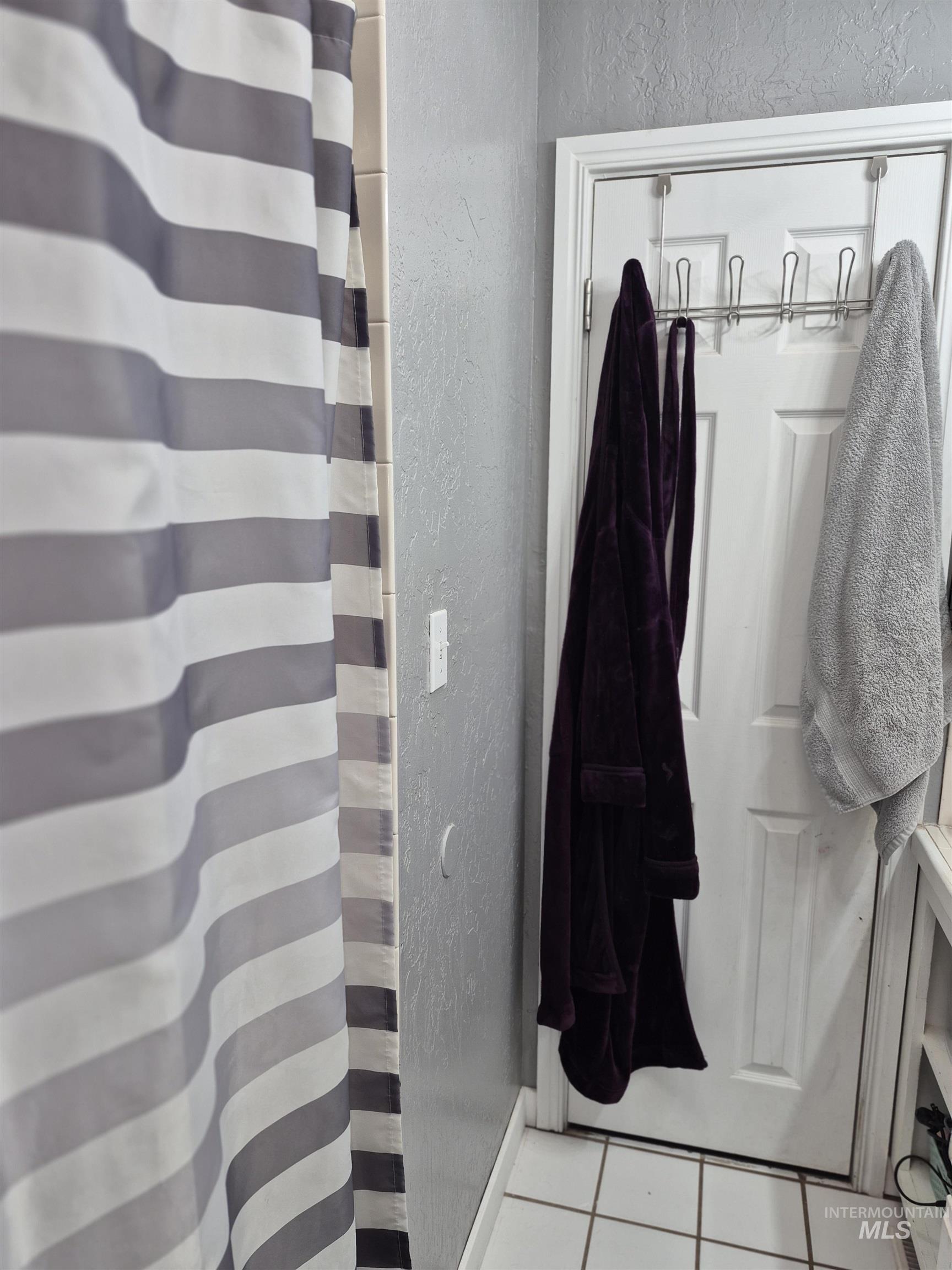Full bath featuring a textured wall, tile patterned flooring, and a shower with curtain
