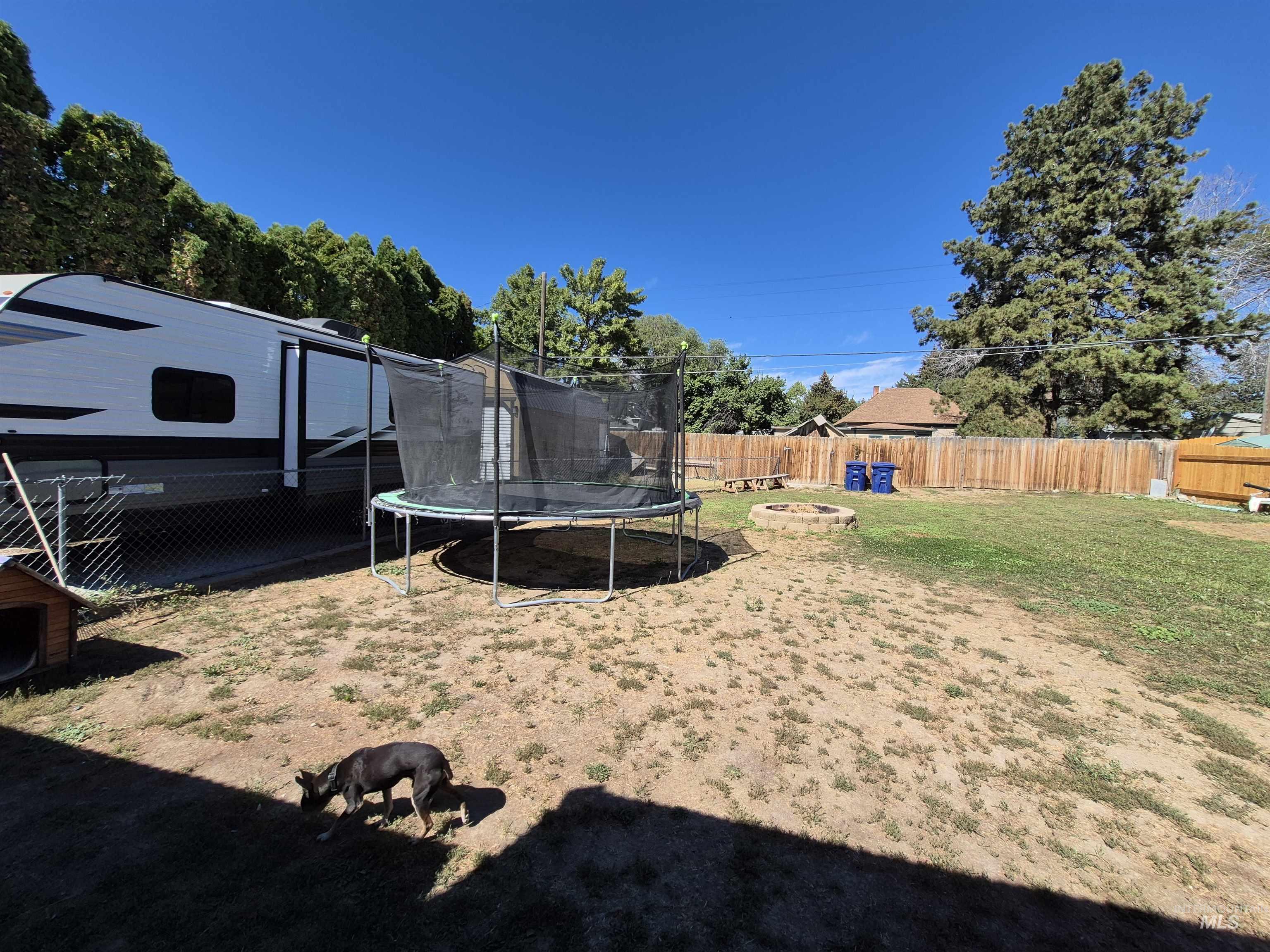 Fenced backyard featuring a fire pit and a trampoline