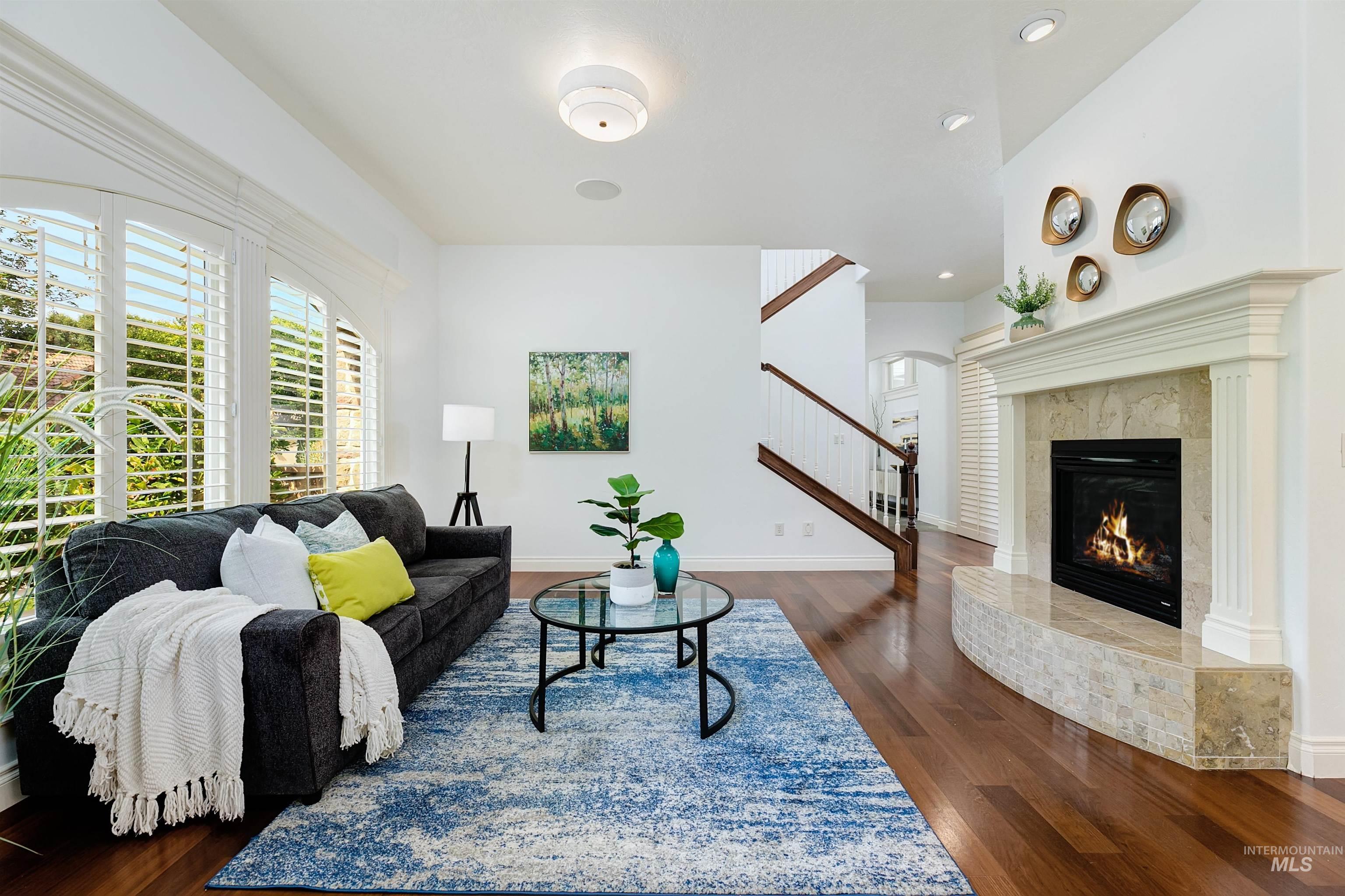 Living area featuring dark wood-style floors, a premium fireplace, recessed lighting, and stairway