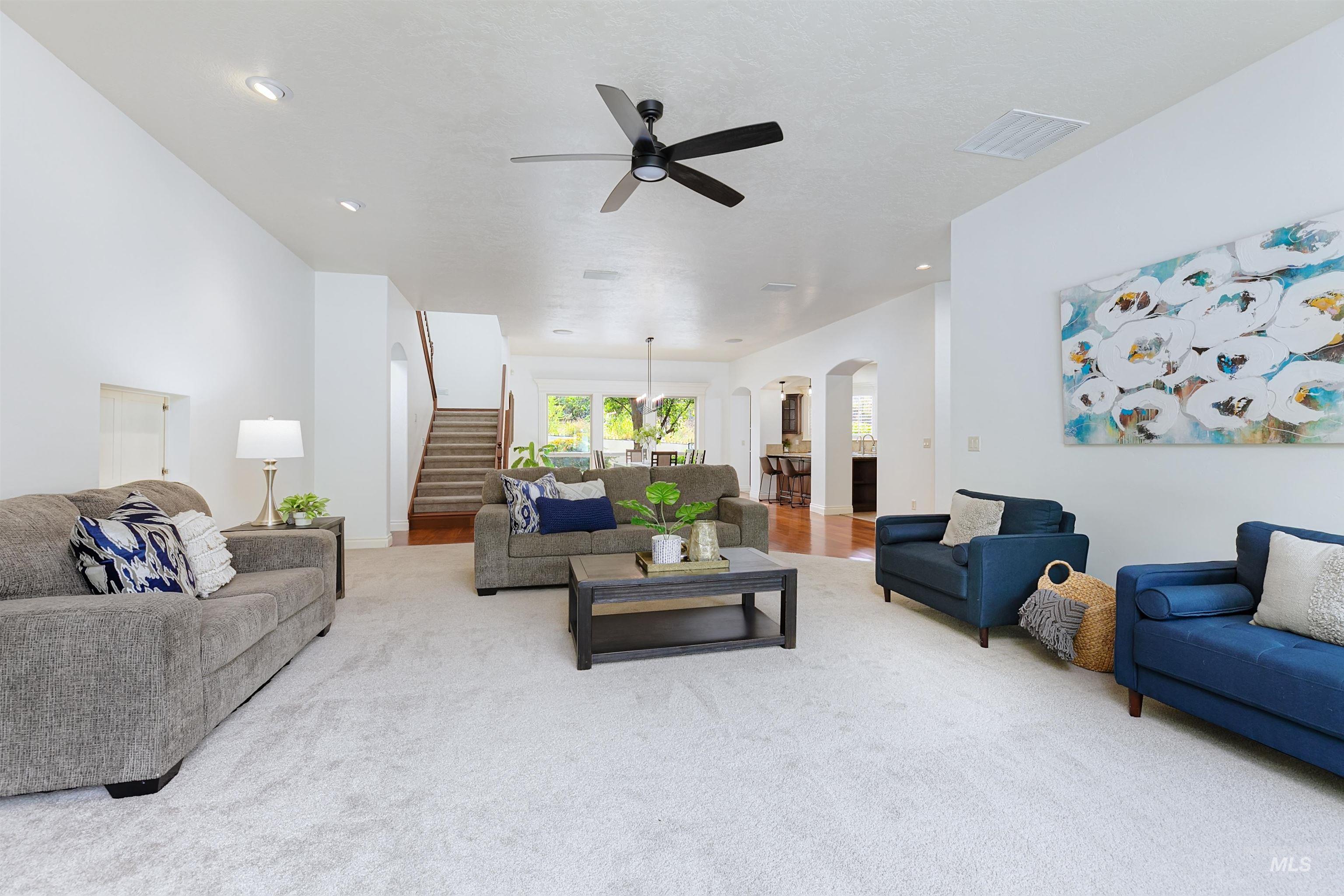 Living room with arched walkways, stairs, carpet flooring, ceiling fan, and recessed lighting