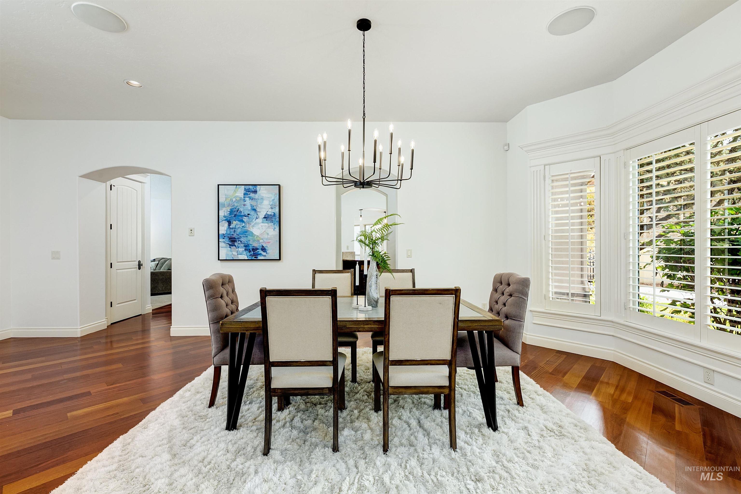 Dining space with arched walkways, a chandelier, dark wood-style floors, and recessed lighting