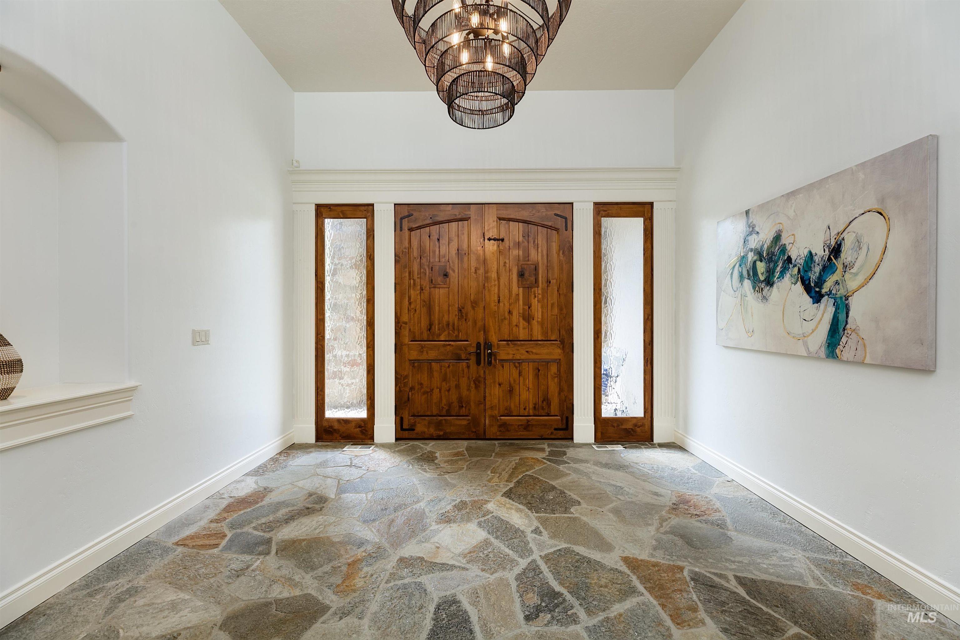 Entrance foyer with stone floors and a chandelier