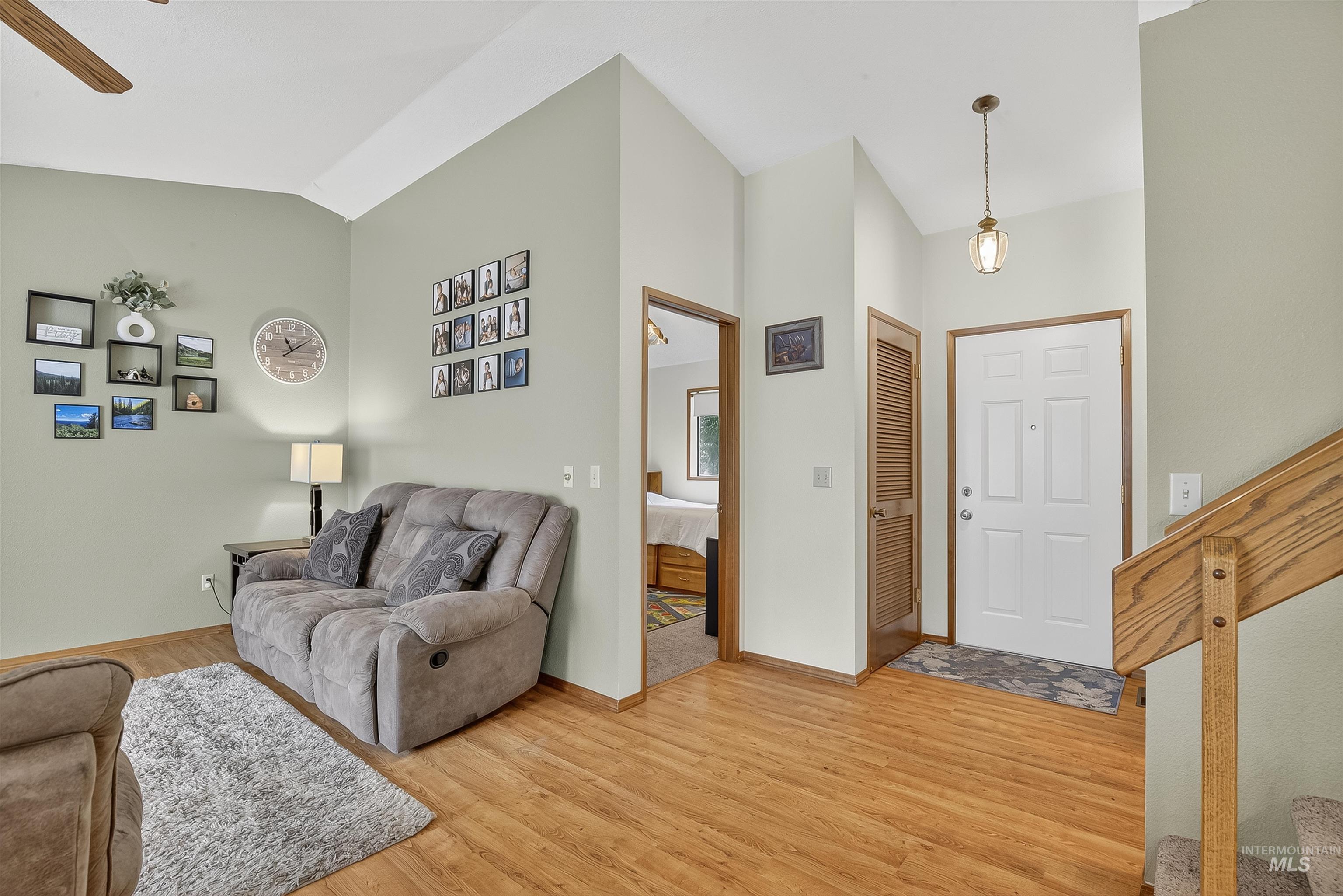 Living room with light wood-style floors, lofted ceiling, and ceiling fan