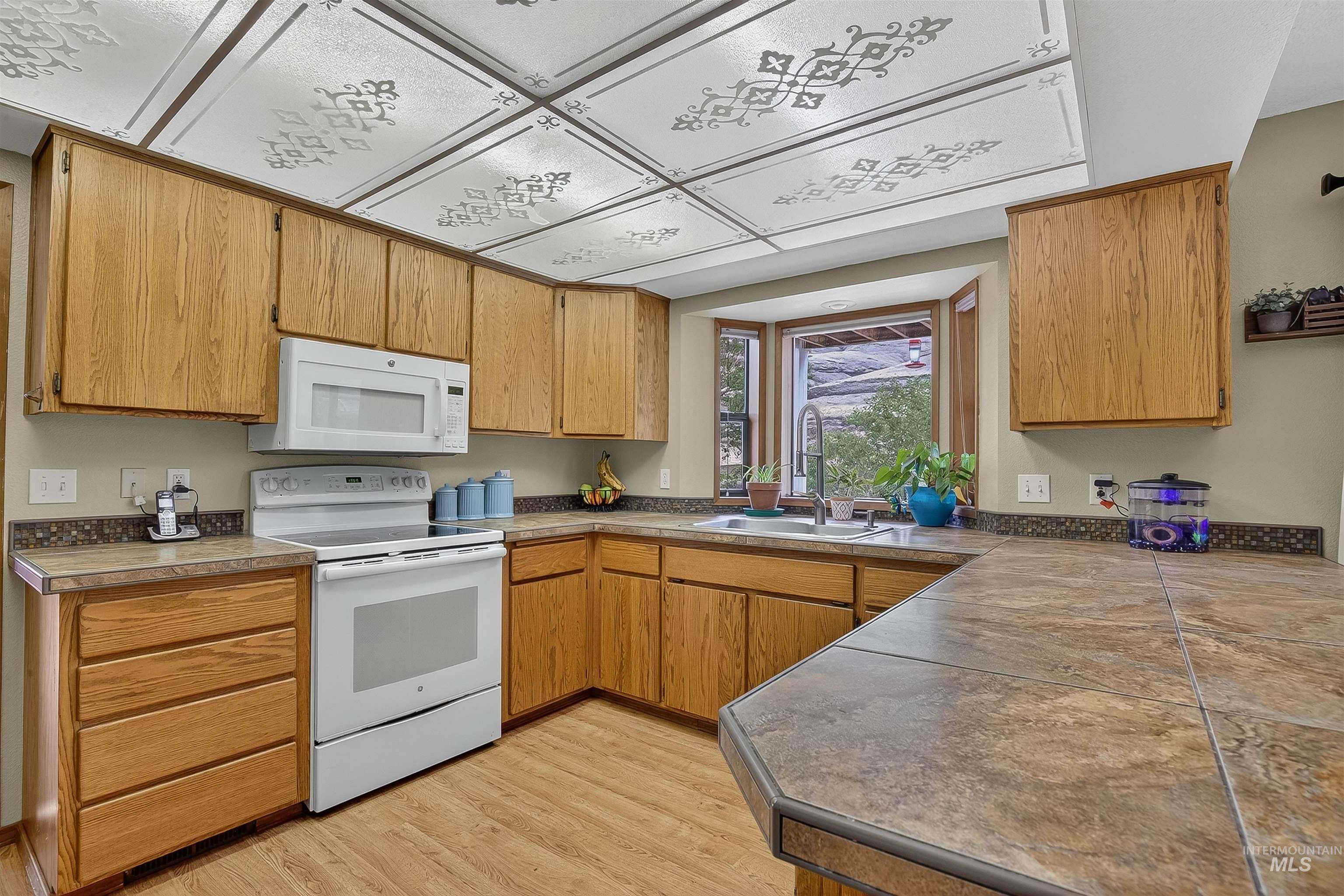 Kitchen featuring white appliances, light wood-style flooring, and brown cabinetry