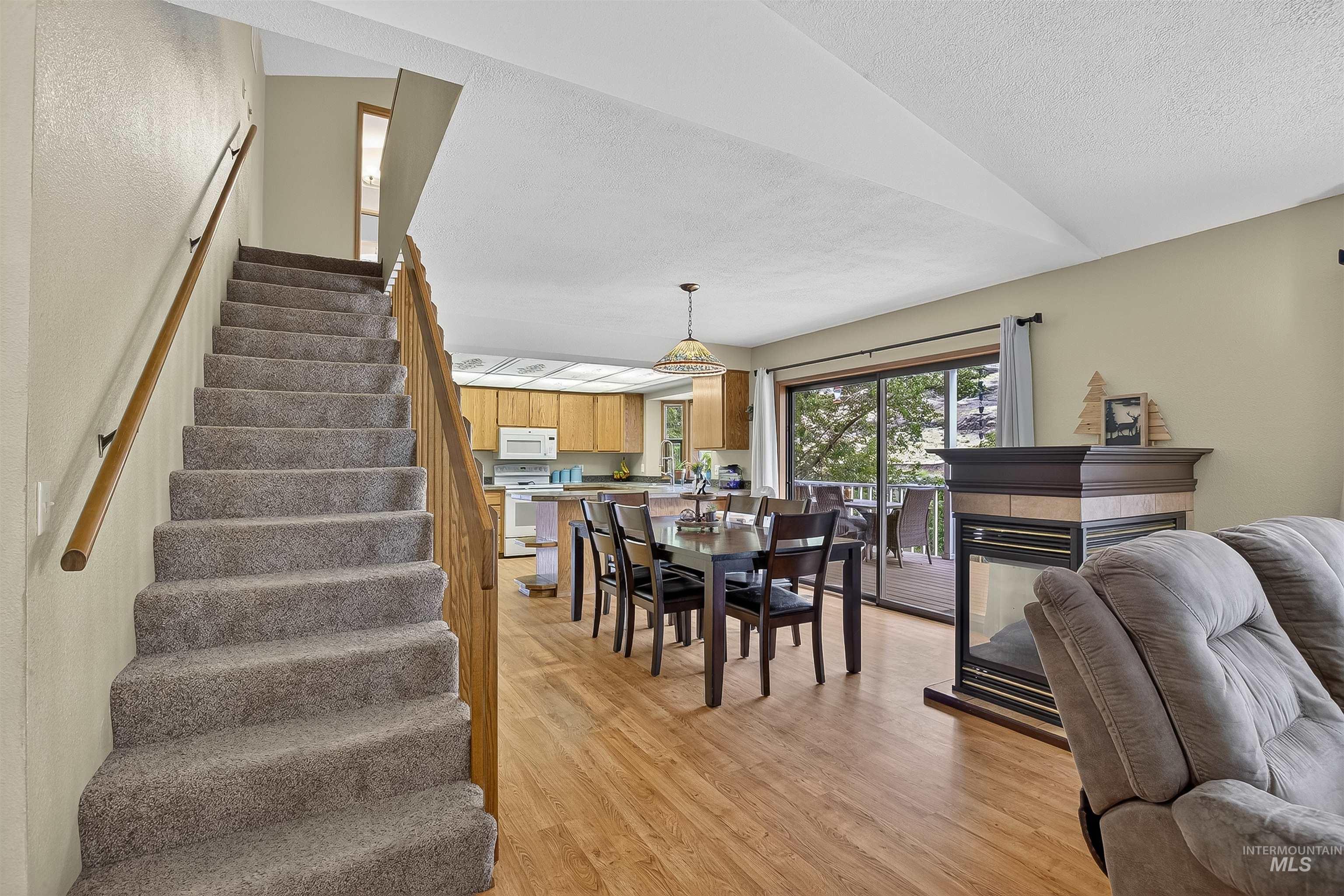 Dining space with stairway, light wood finished floors, a fireplace, and a textured ceiling